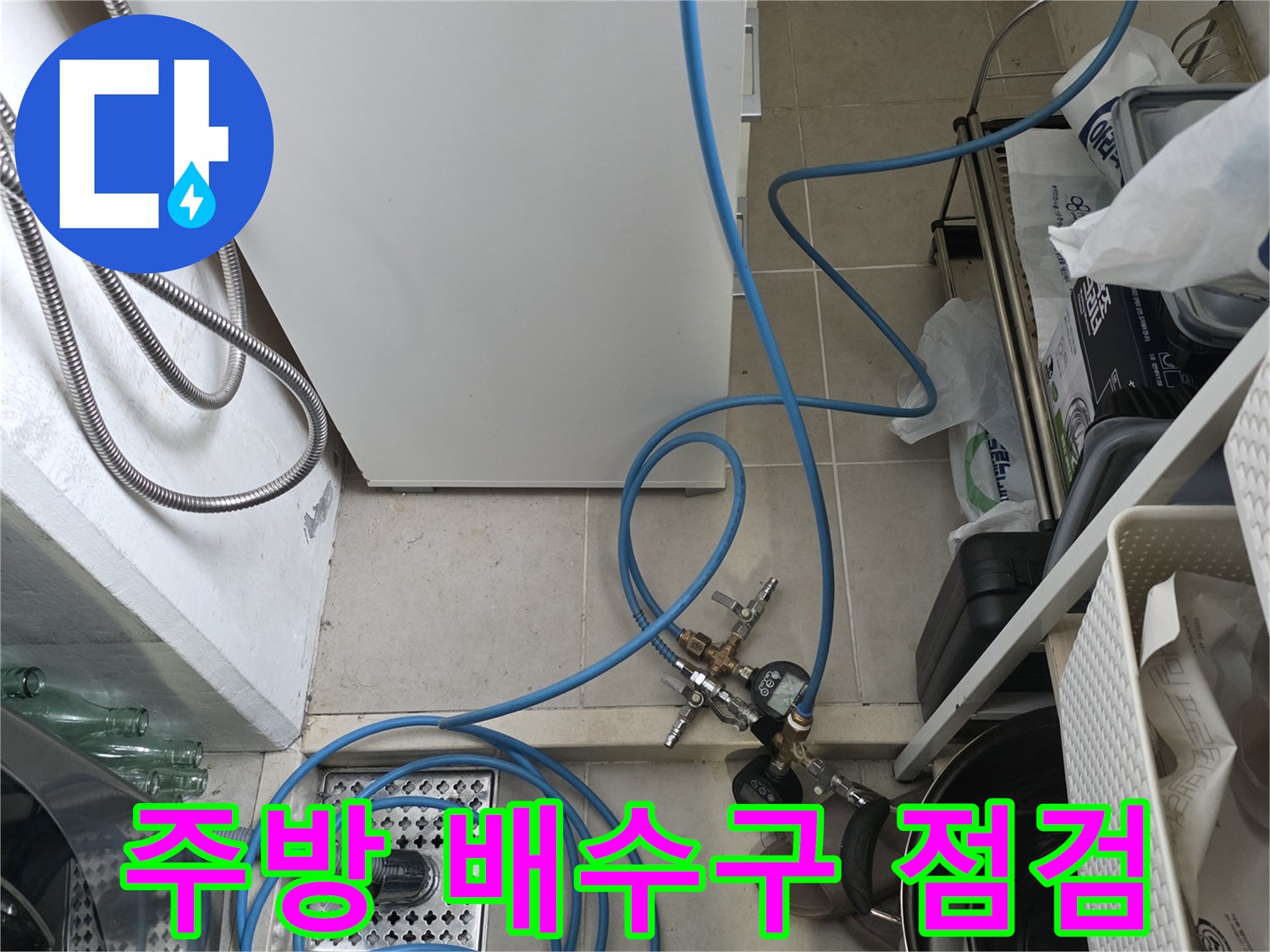 싱크대 하부장 내부의 정수기 호스와 배수관 연결 상태를 확인하는 모습