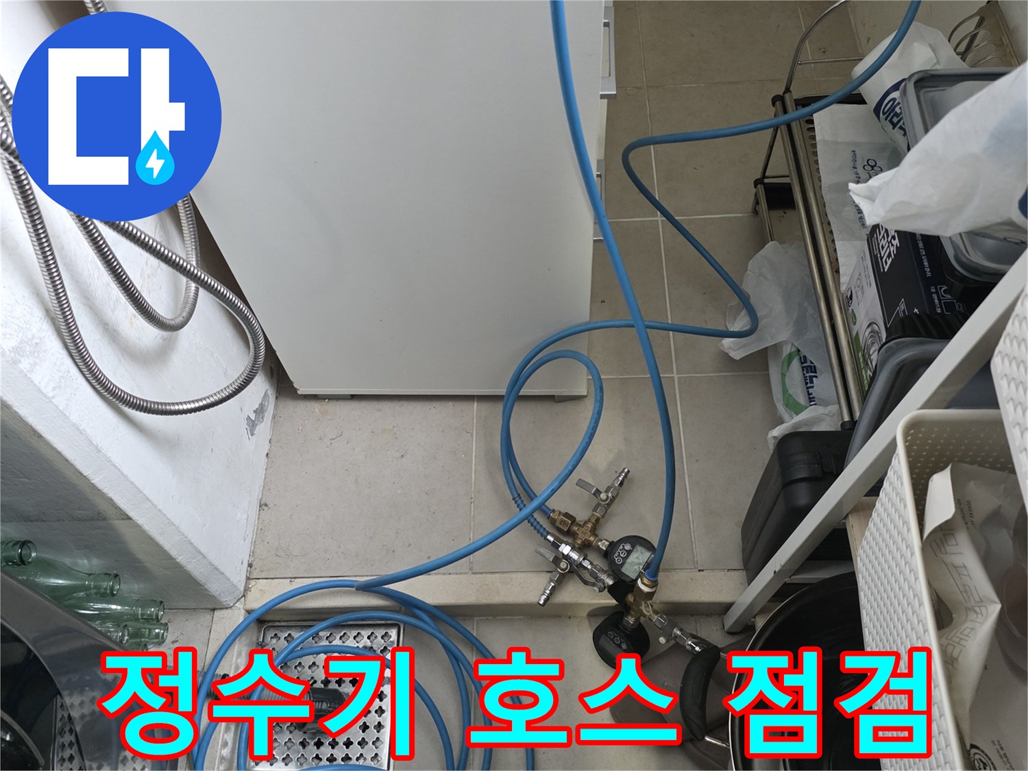 파란색 호스와 압력계가 연결된 싱크대 하부 배관 작업 모습