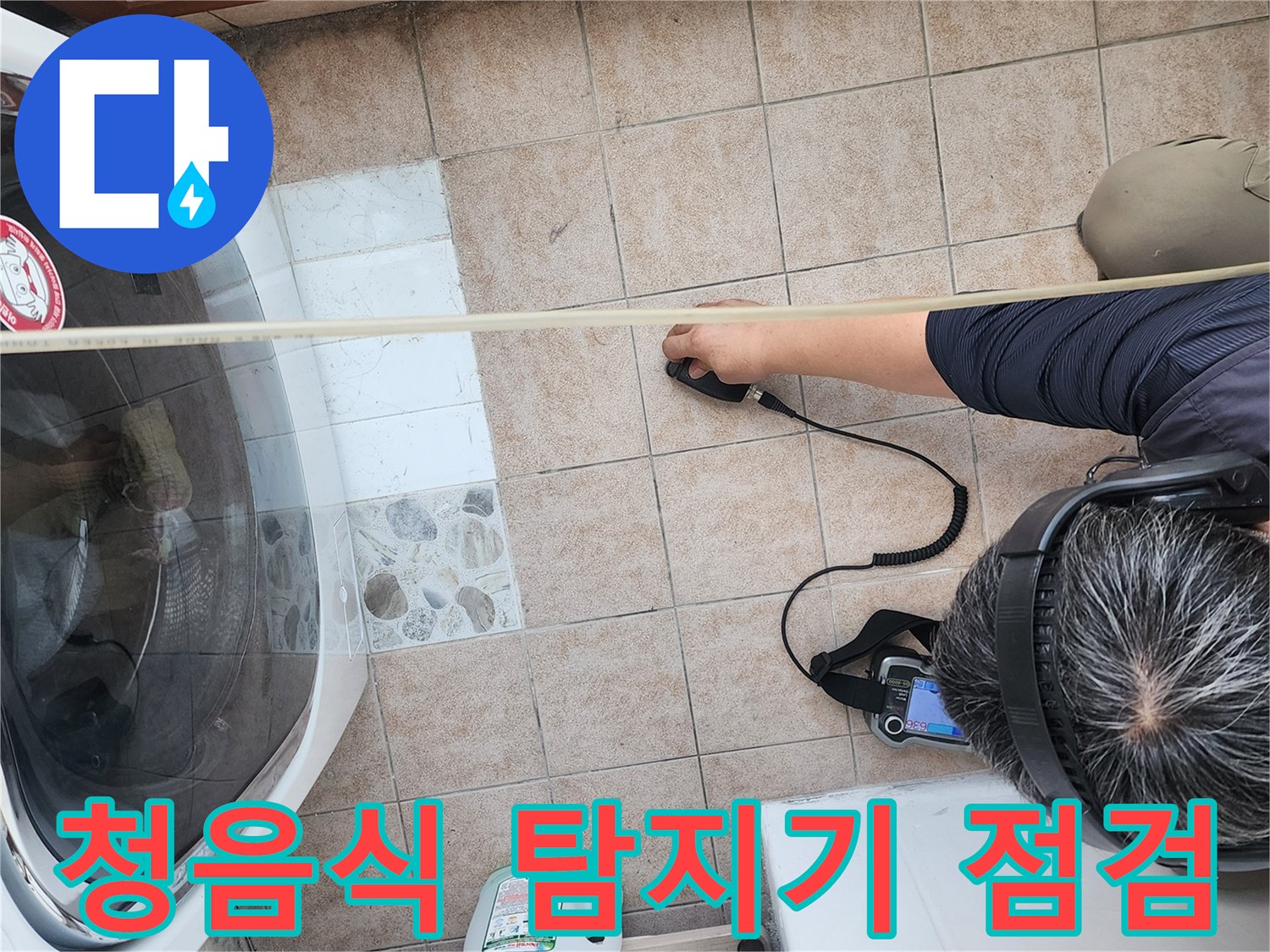 세탁실 바닥 타일 위에서-청음식 탐지기를 사용하여-누수 지점을 추적하는 모습