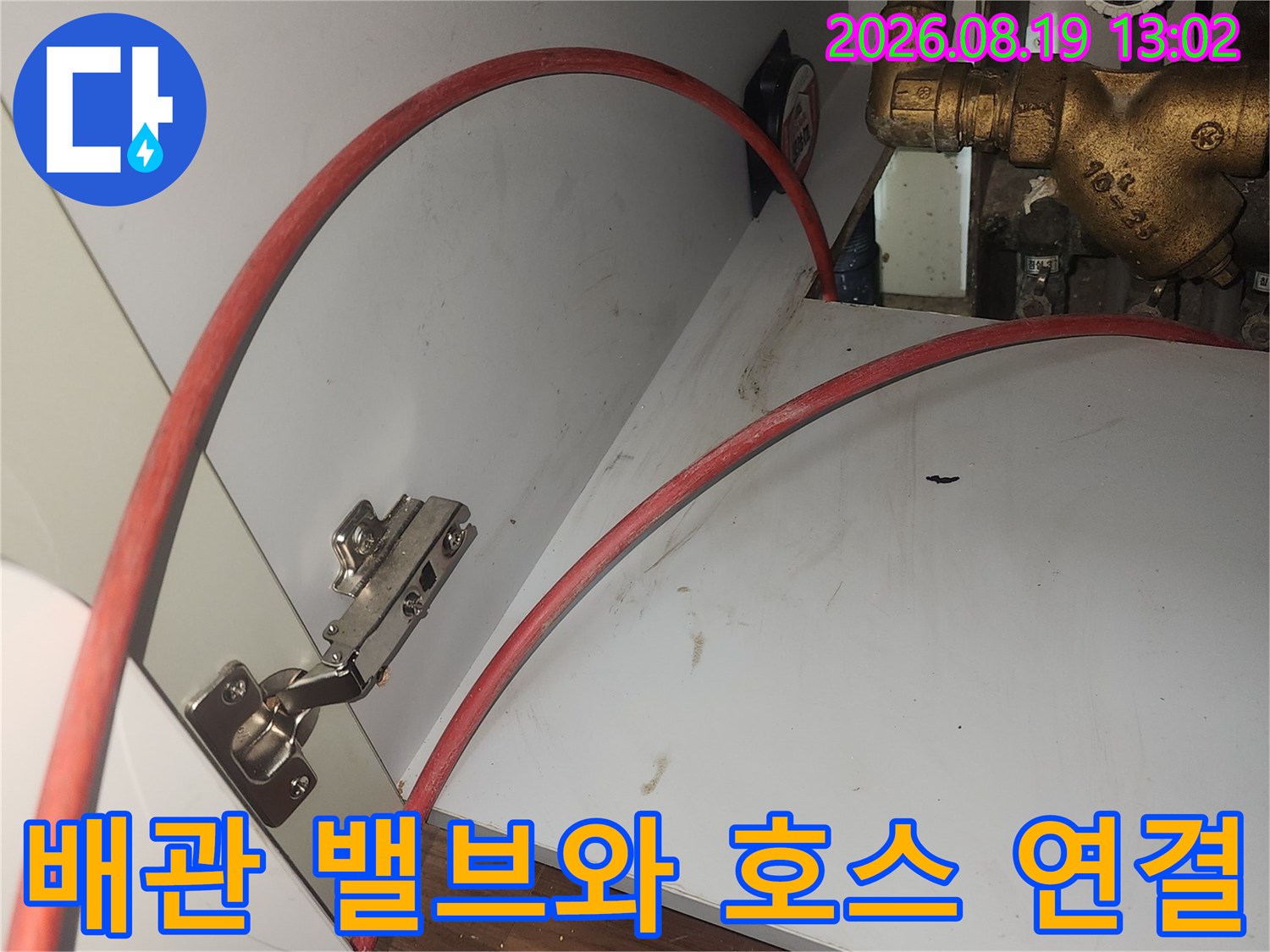 싱크대 하단 금속 밸브 및 붉은색 배수 호스 상세 사진