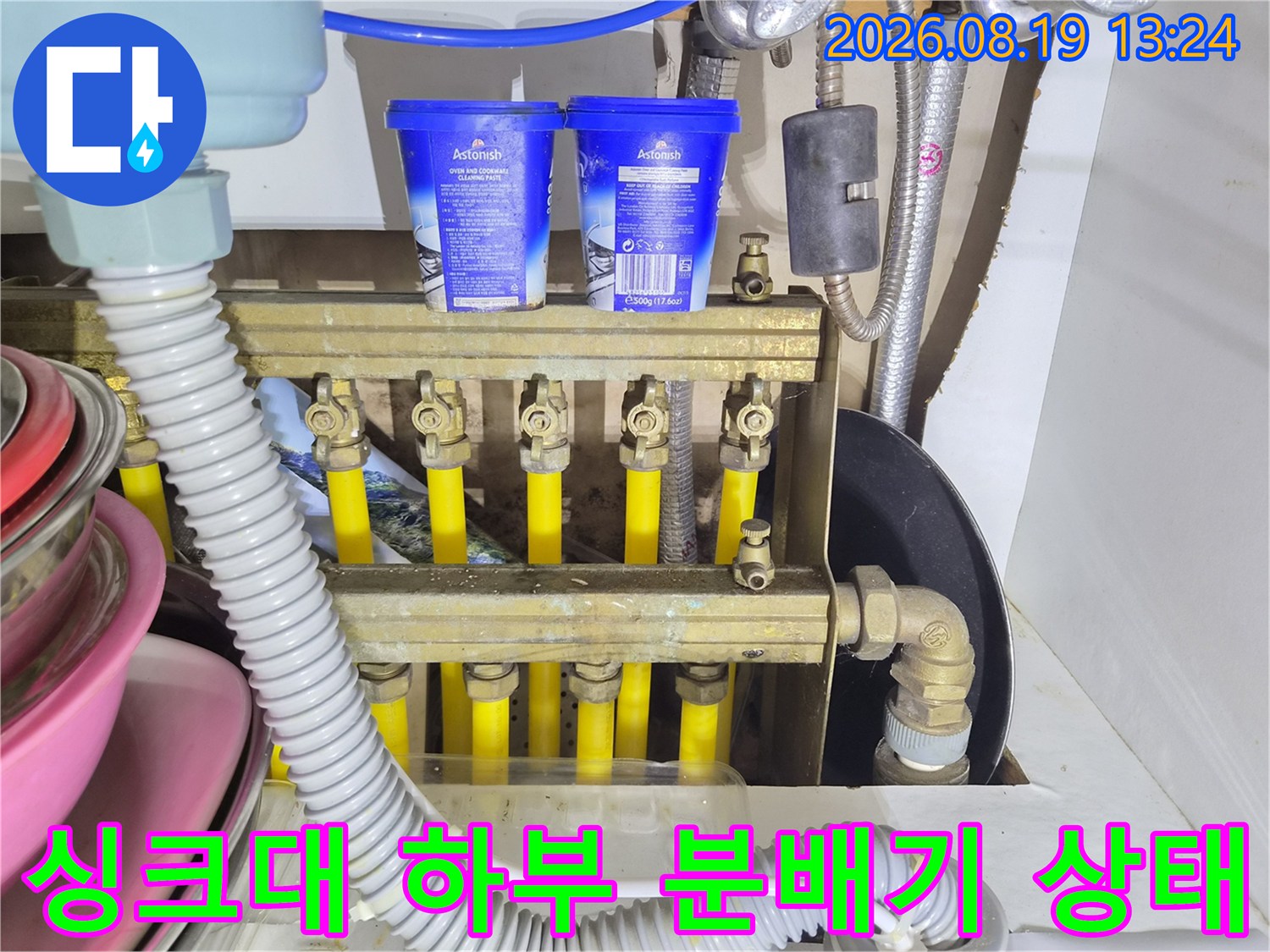 싱크대 아래 배관 분배기와 연결된 노란색 난방 배관들의 모습입니다.