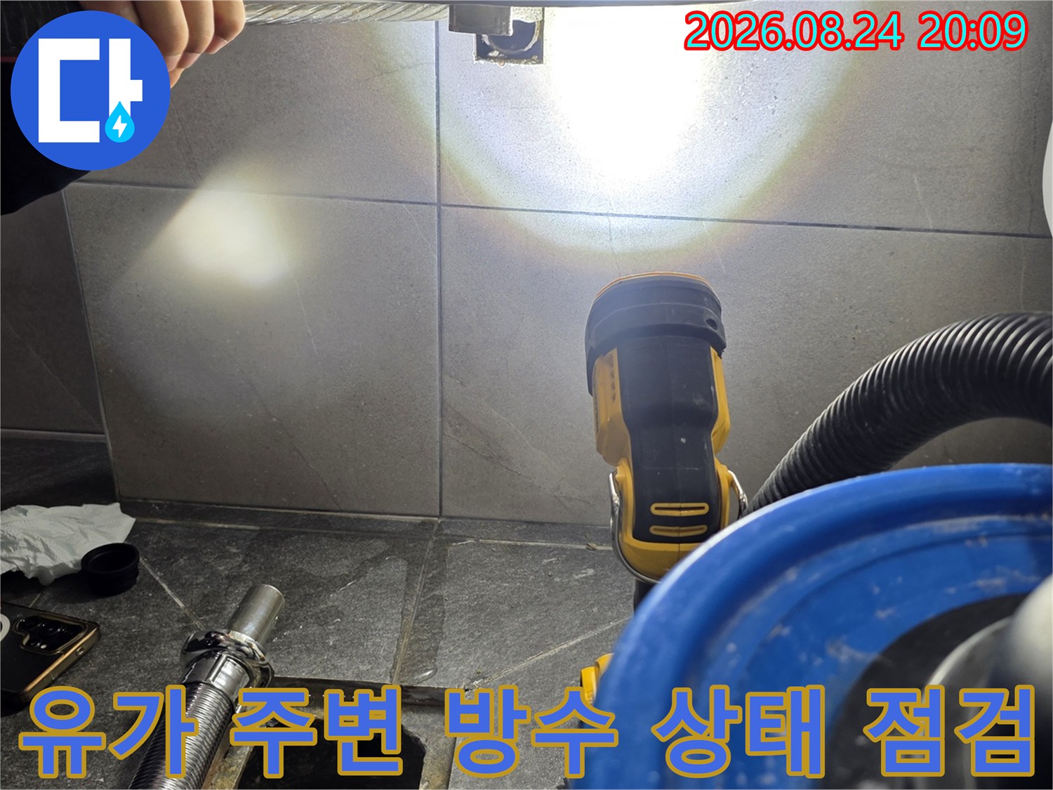 전동 공구와 조명을 사용하여 배수구 주변의 누수 흔적을 조사합니다.