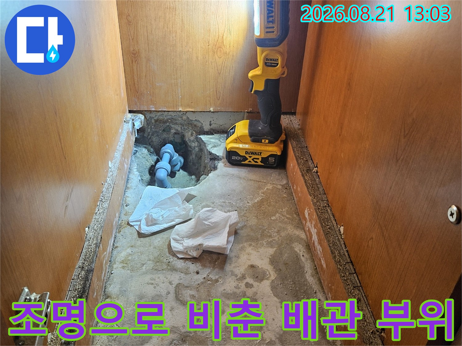손전등 조명을 사용하여 싱크대 하부 배관의 누수 여부를 확인 중입니다.