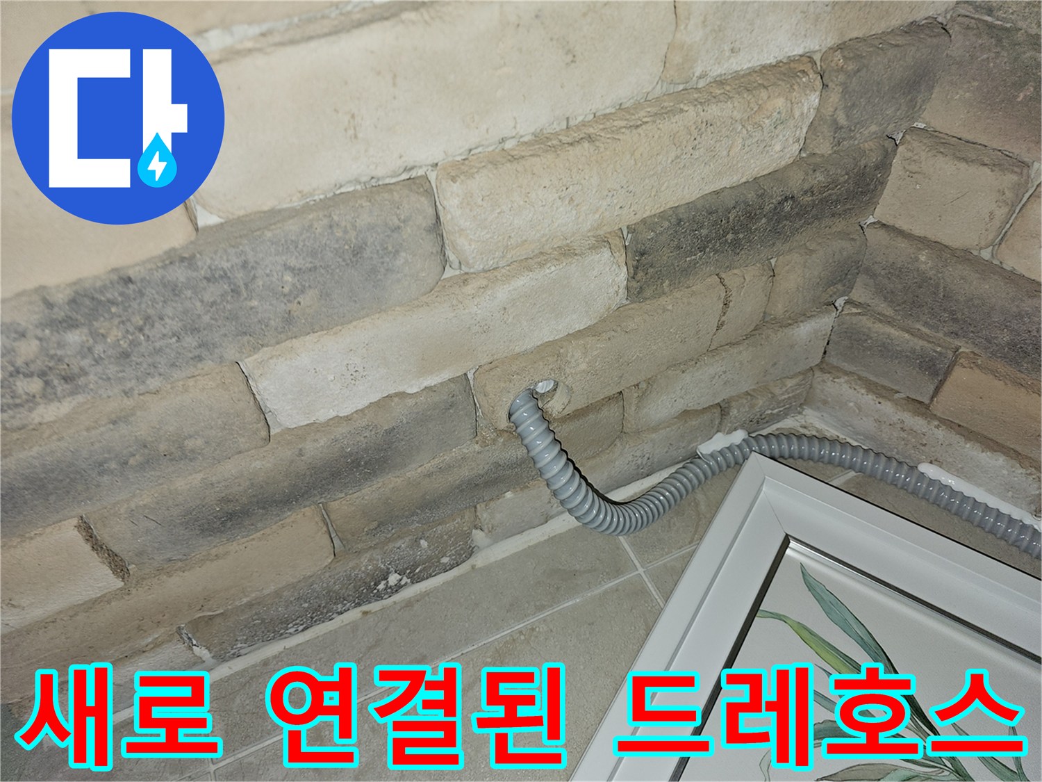 벽면 하단에 설치 완료된 회색 주름관 배수 호스