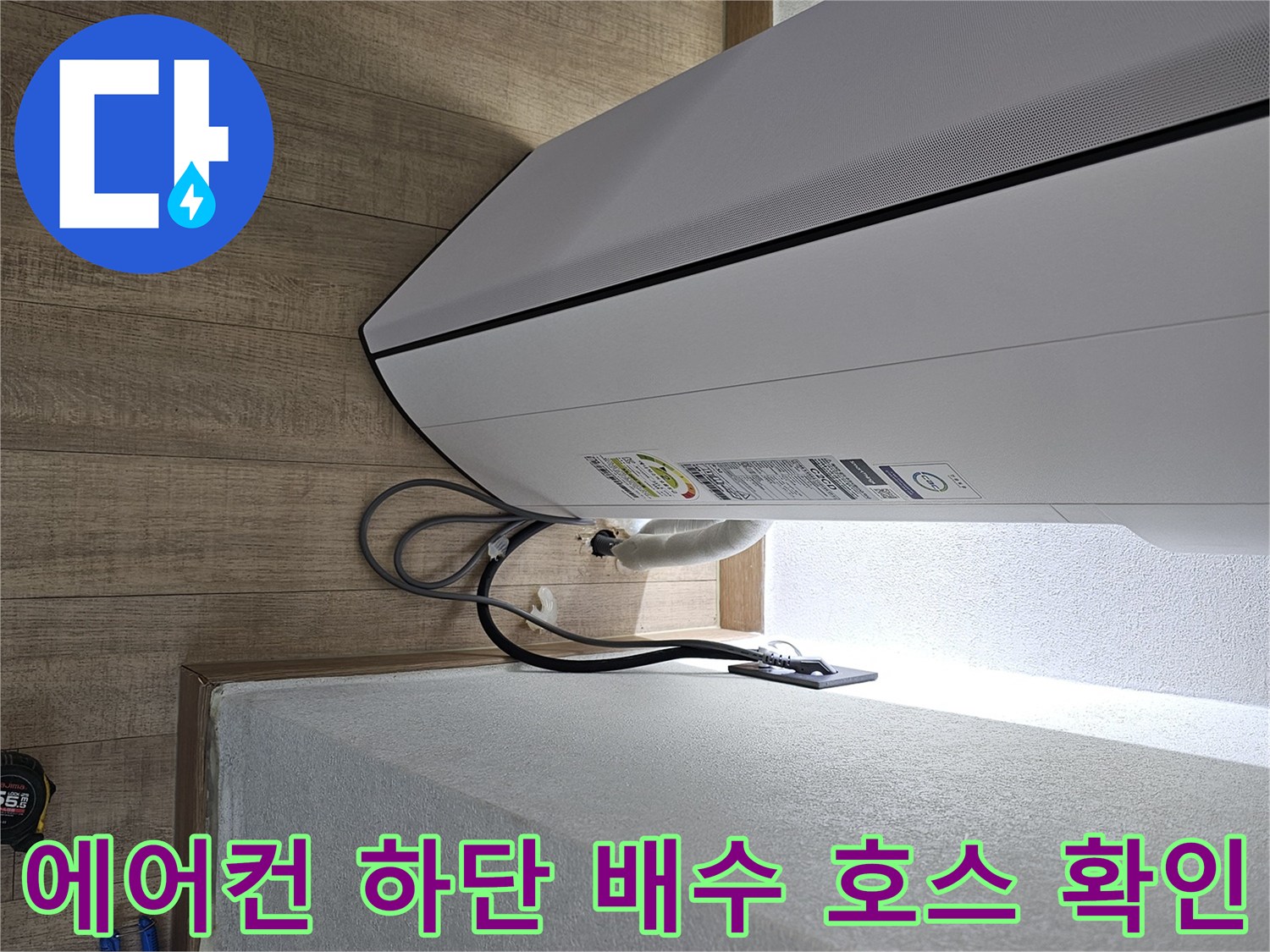 에어건 본체 아래쪽의 드레인 호스와 벽면 사이 연결 상태를 보여주는 사진입니다.