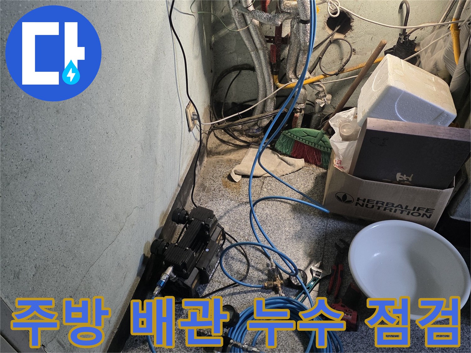 싱크대 하부의 은색 수도 배관과 파란색 압력 측정용 호스 배치