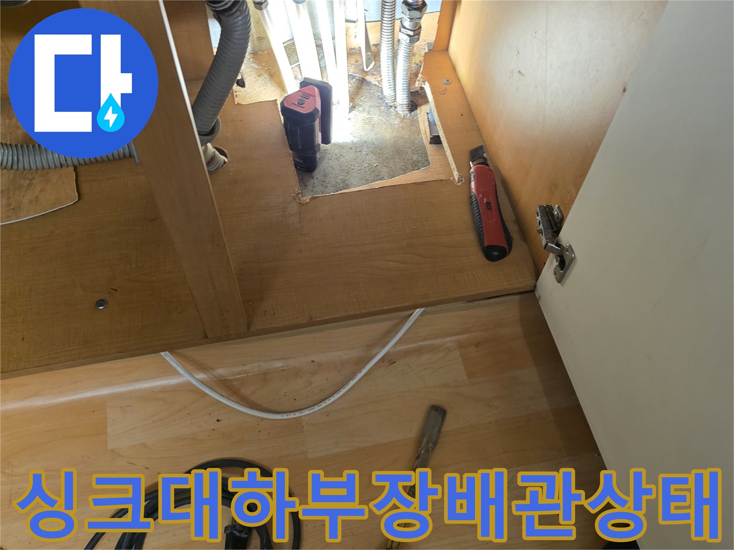 싱크대 하부장 내부의 노출된 온수 배관과 주름관 연결 부위 현장 모습