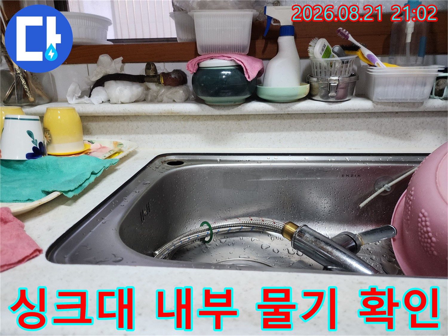 싱크대 내부의 수전 호스와 배수구 주변에 맺힌 물방울 모습입니다.