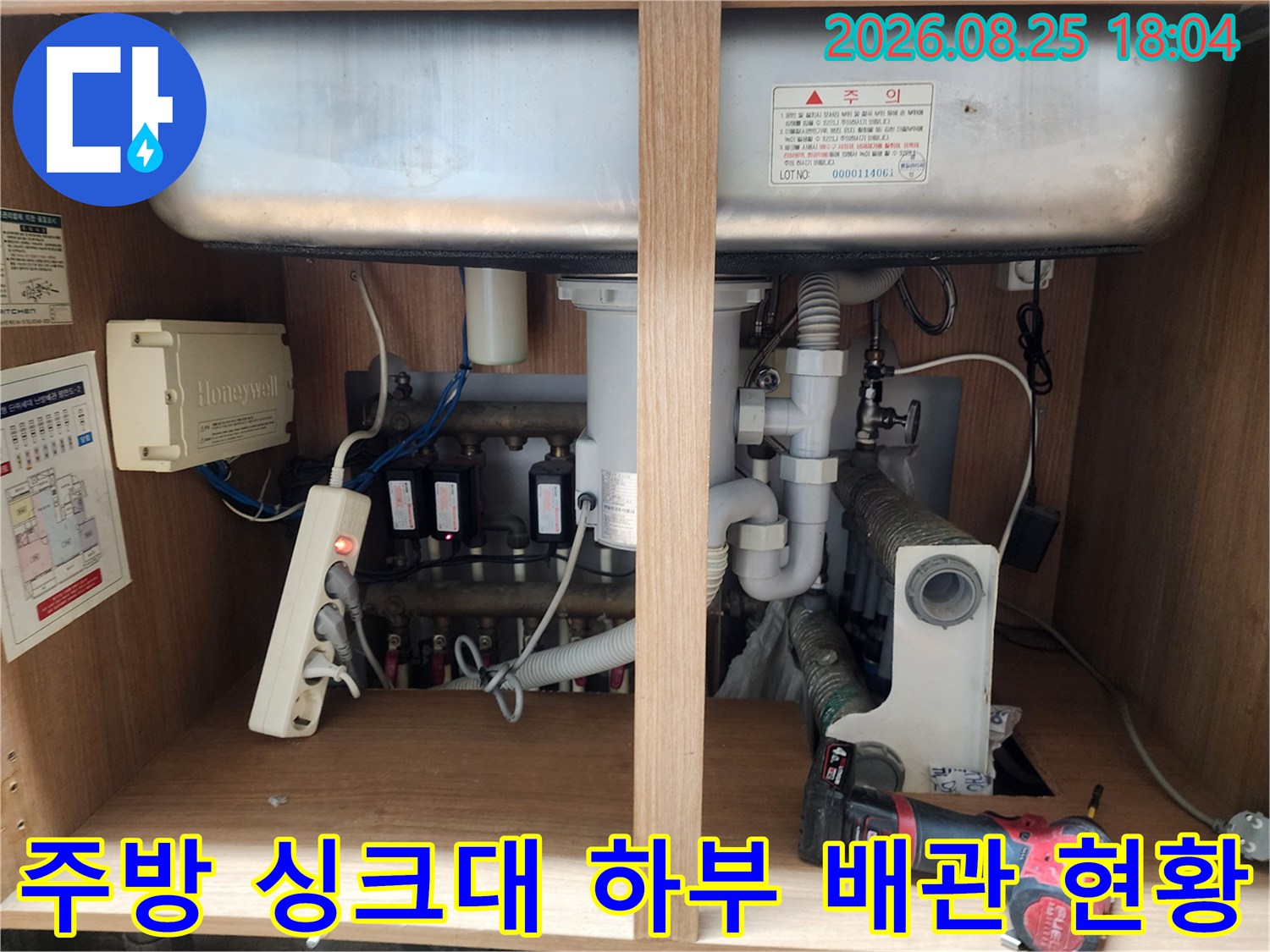 싱크대 아래쪽의 복잡한 배수 호스 및 전기 제어 장치 점검 상황