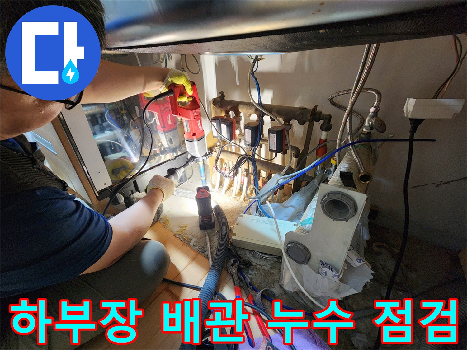 싱크대 하부장 내부의 복잡한 배수 배관과 연결 부위 점검 중