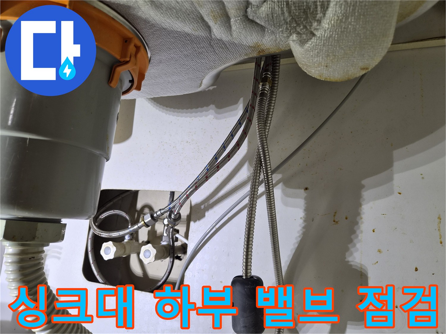 싱크대 밑 냉온수 밸브와 은색 금속 호스 연결 부위 상세 모습