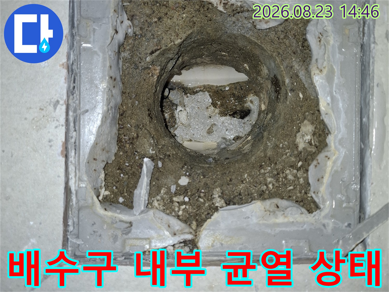 배수구 배관 주변의 갈라진 방수층과 퇴적된 이물질을 촬영한 사진입니다.