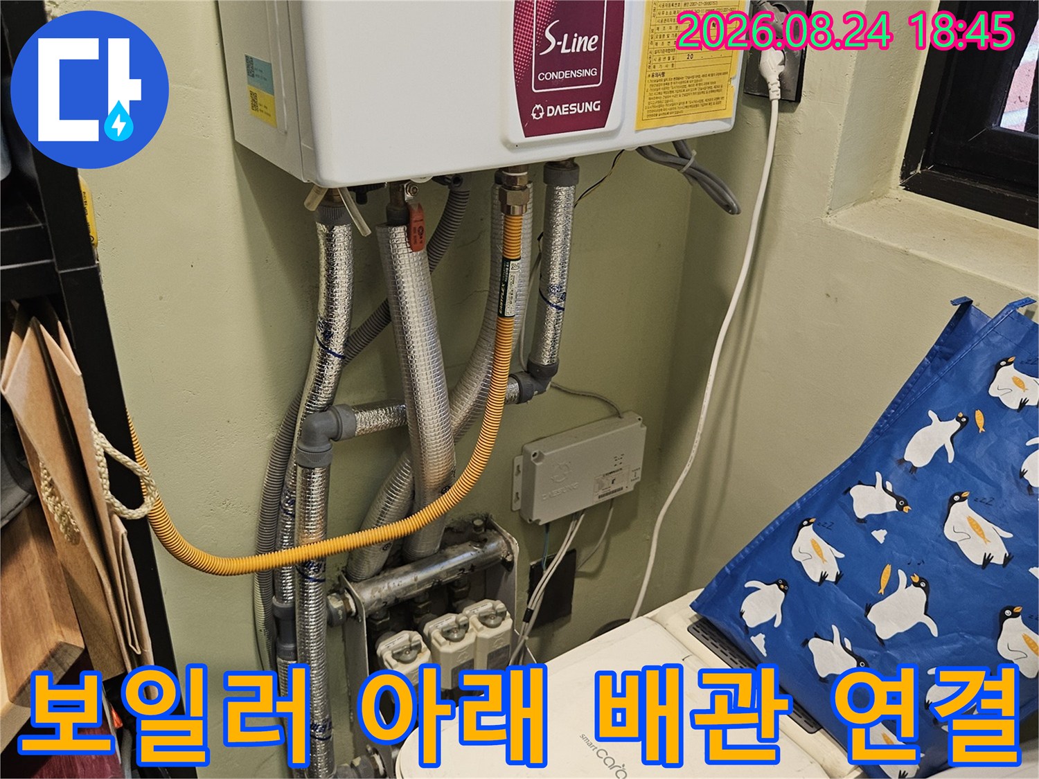 보일러 하단의 은색 보온재와 노란 호스 연결 부위 상세