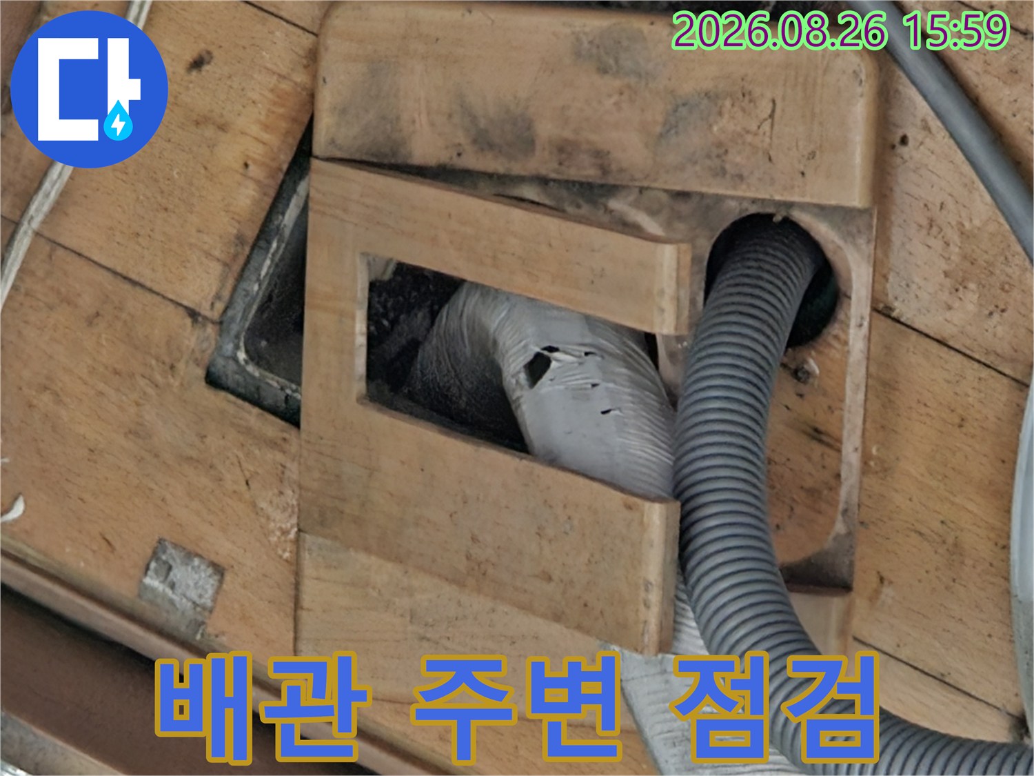 나무판 아래 배수관과 주변 구조물을 촬영한 사진입니다.