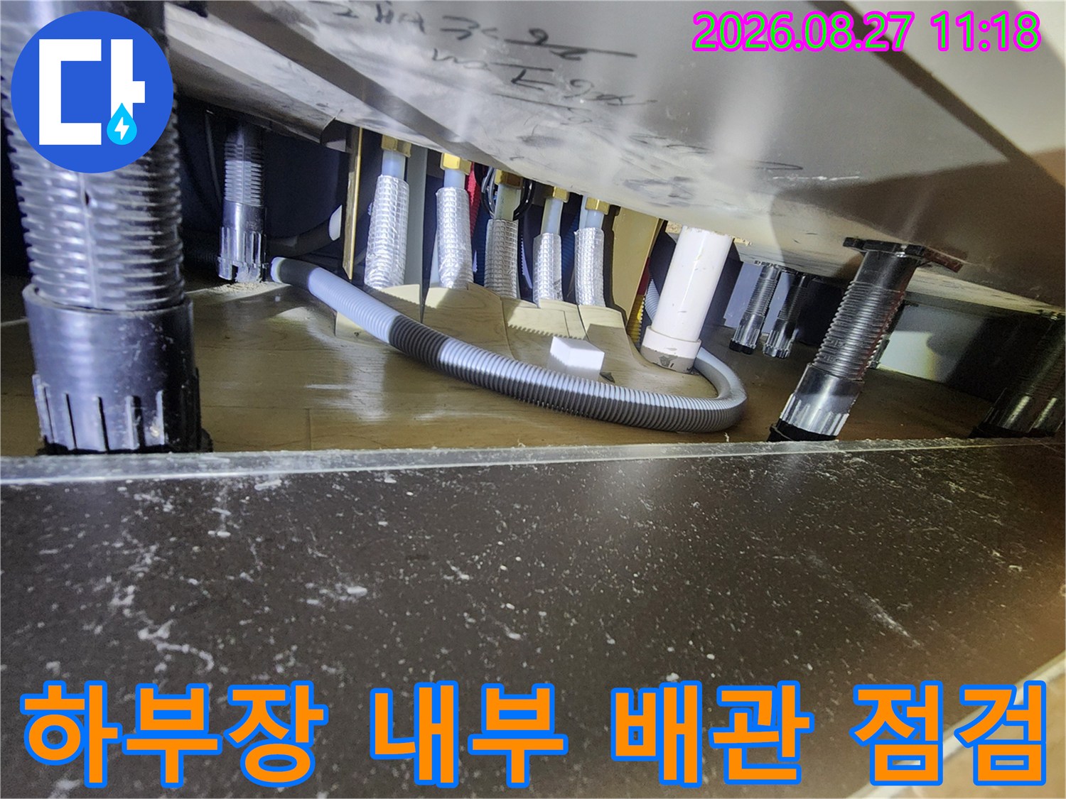 싱크대 하부장 안쪽의 검정색 및 흰색 배관 연결 부위 상세 사진
