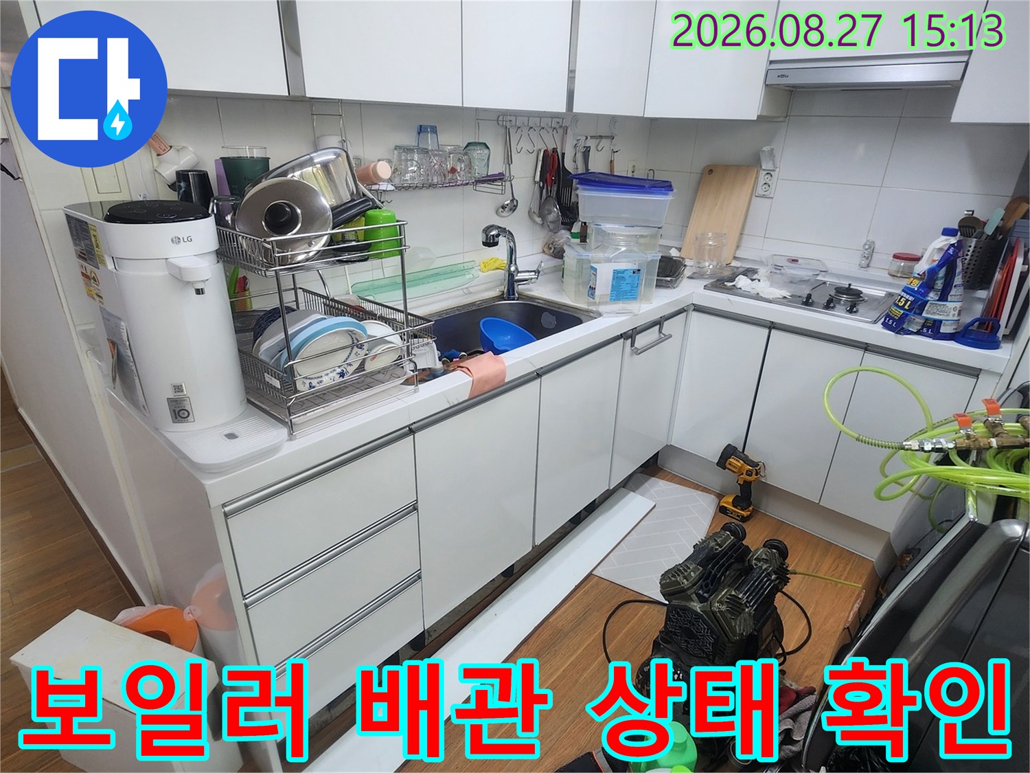 싱크대 하부장 내부에 위치한 보일러 분배기와 연결된 배관들을 상세히 점검하는 장면입니다.