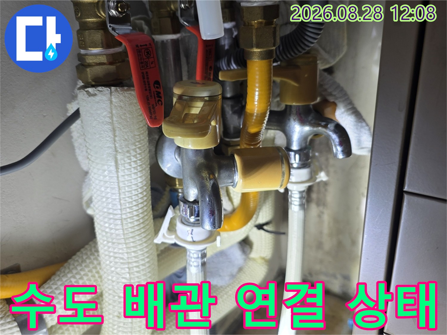 노란색 보온재가 감겨 있는 싱크대 하부의 수도 배관과 밸브 모습입니다.