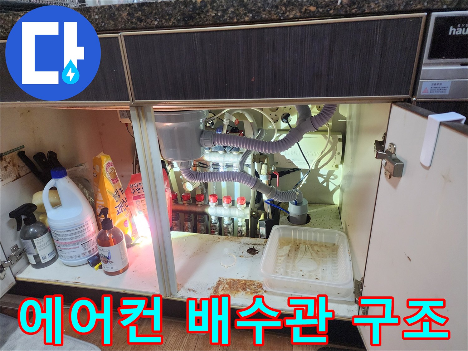 복잡하게 연결된 에어컨 응축수 배출 배관과 하부장 내부 모습