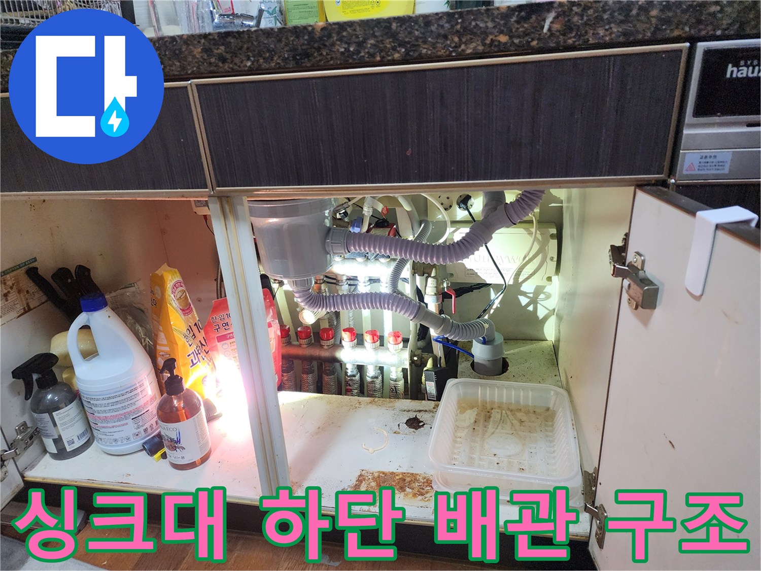 싱크대 아래 에어컨 배수 호스와 주변 물건들