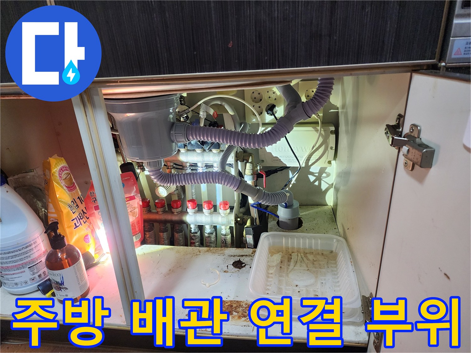 싱크대 하단부의 에어컨 배수 호스 및 다중 배관 구조 모습