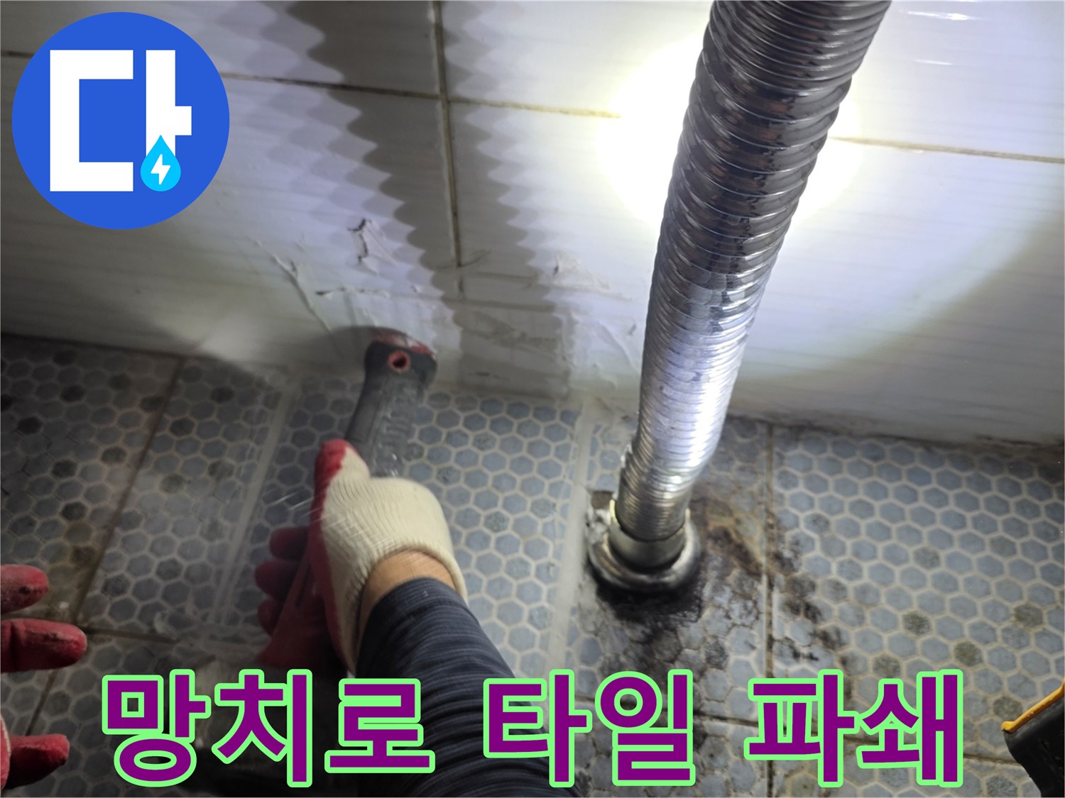 작업자가 장갑을 끼고 망치를 사용하여 바닥 타일을 부수는 작업 모습입니다.