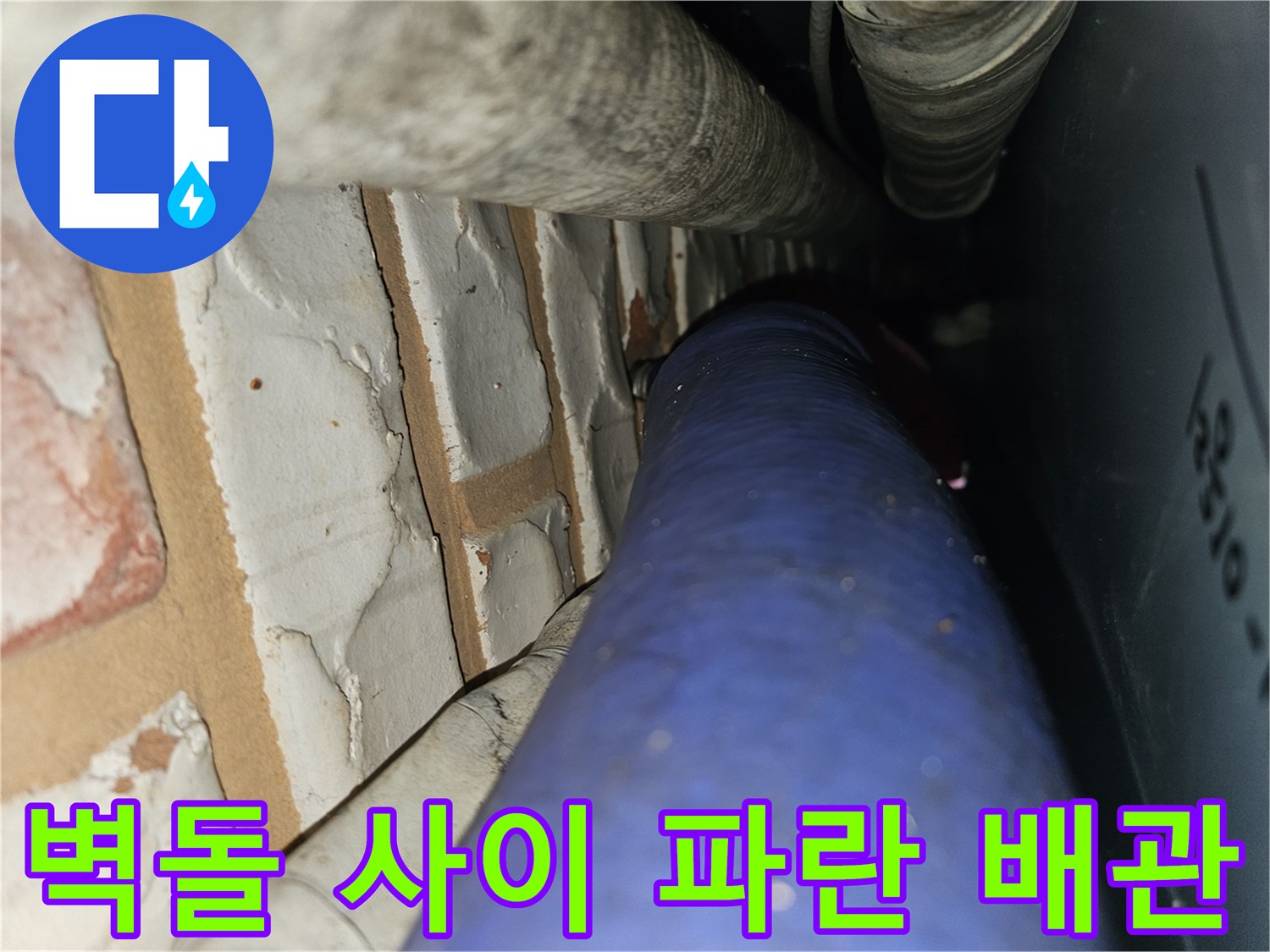 벽돌 벽면을 따라 설치된 파란색 수도 배관 상세 사진