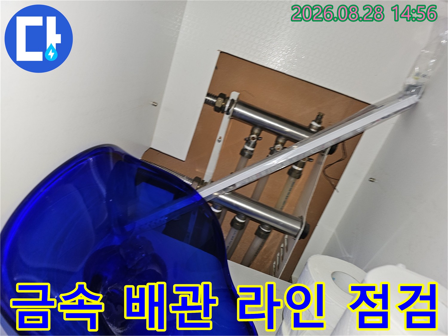 싱크대 하단부에 위치한 금속 재질의 보일러 및 수도 배관들의 배치 상태입니다.