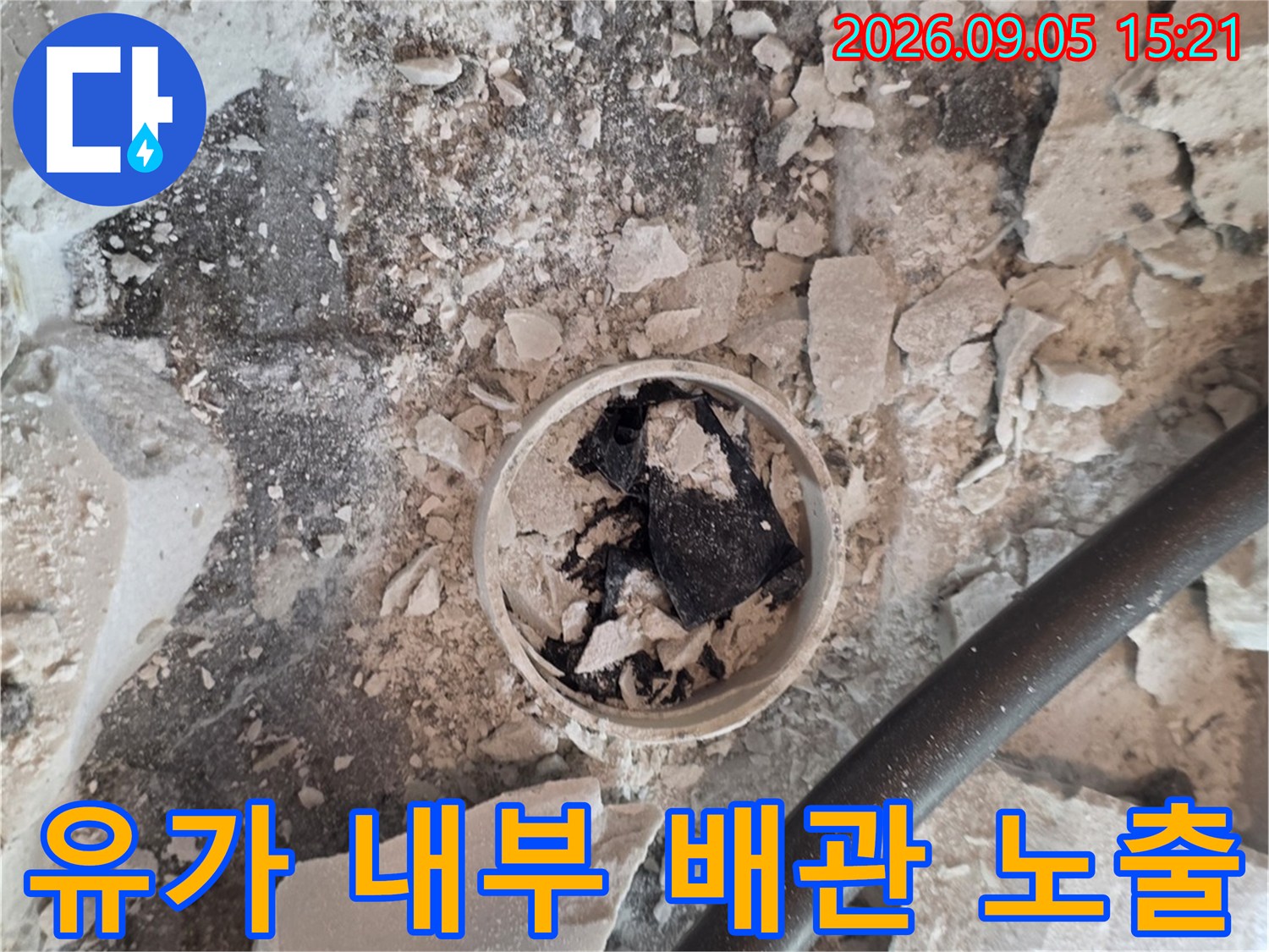 배수구 유가 주변의 타일 파편과 드러난 배관 연결부