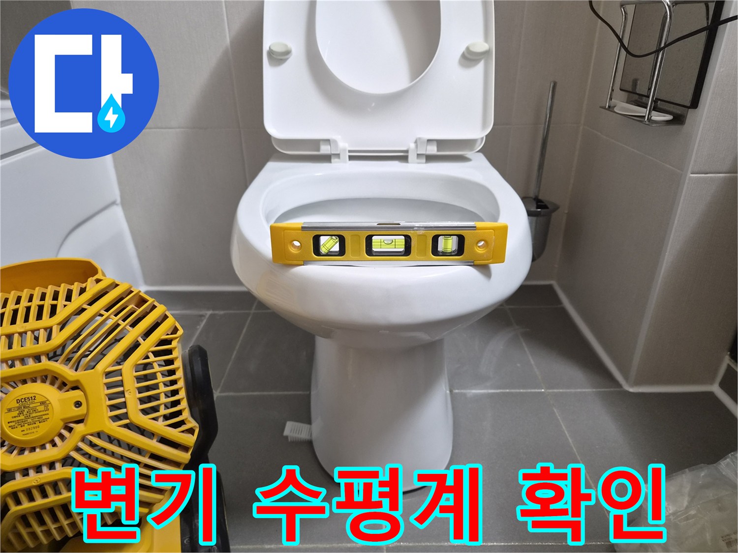 변기 시트 위에 놓인 노란색 수평계와 작업 장비