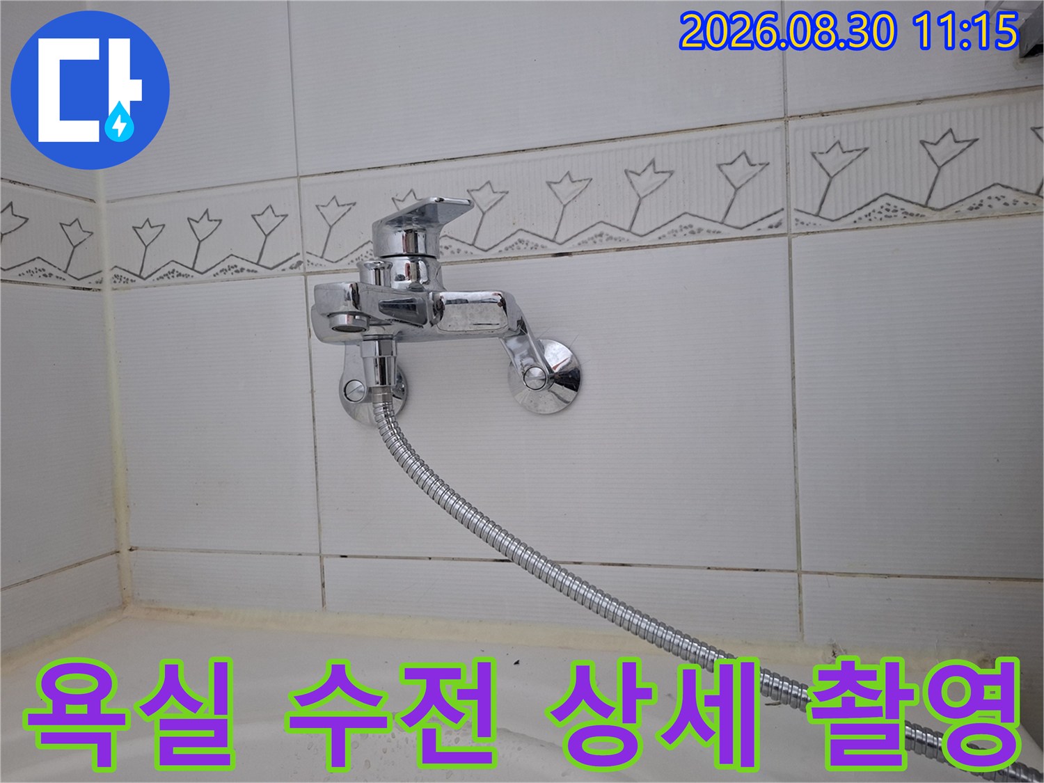 벽면에 설치된 은색 샤워기 수전과 호스 연결부