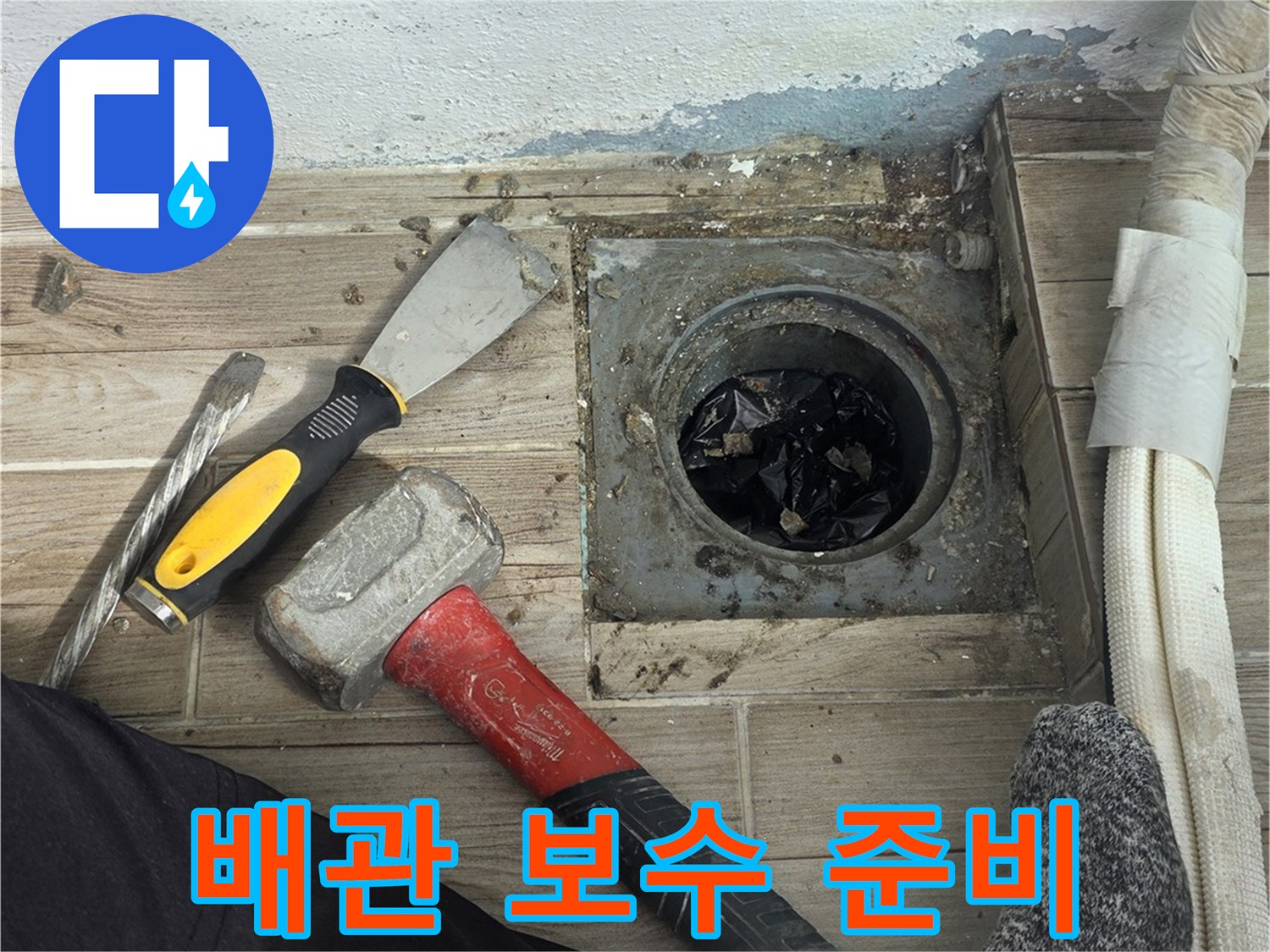 망치와 공구를 사용하여 배관 주변을 정리하는 작업자 모습
