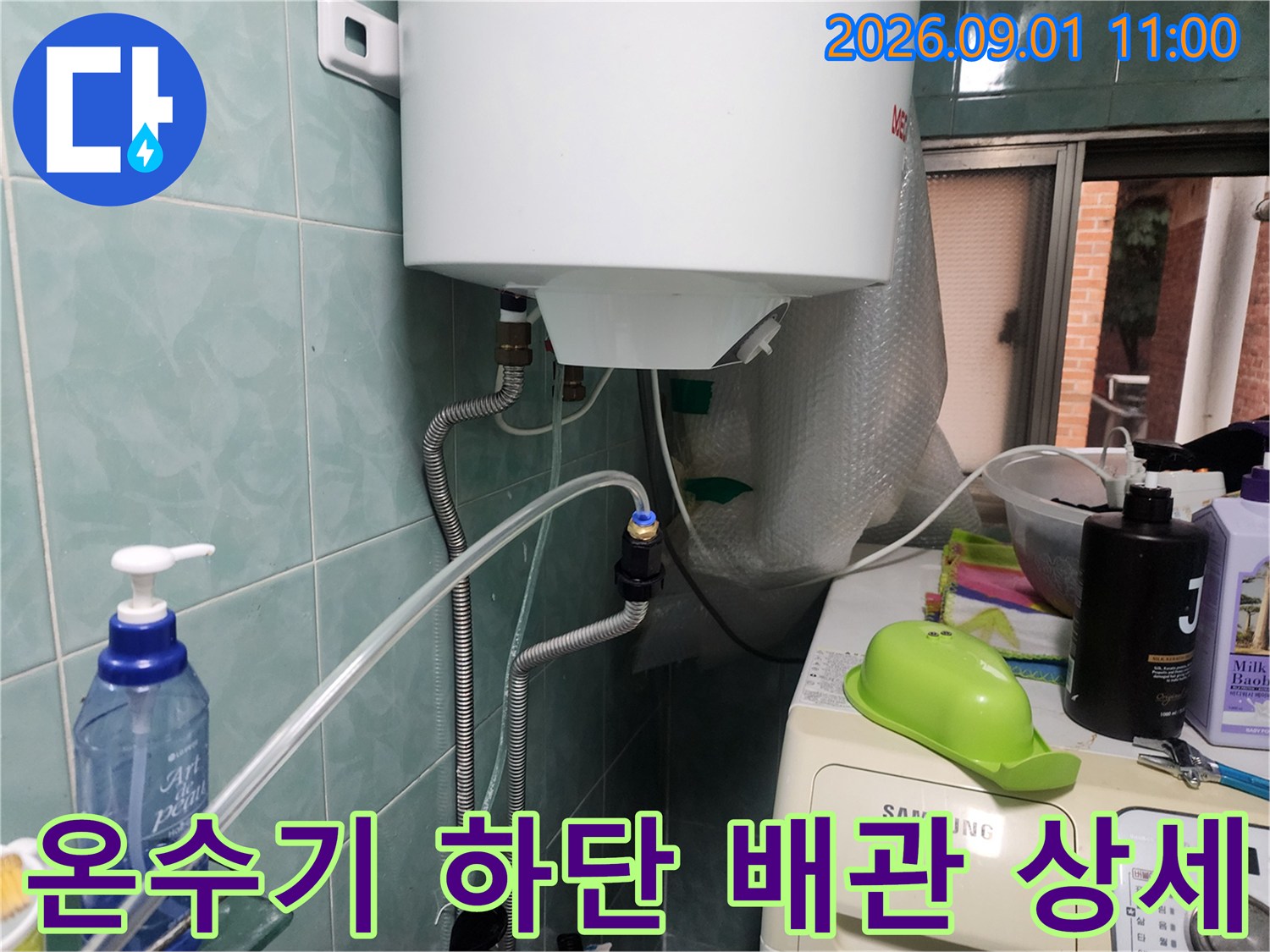 벽면 타일과 온수기 하단 배관 및 밸브 연결 부위 모습