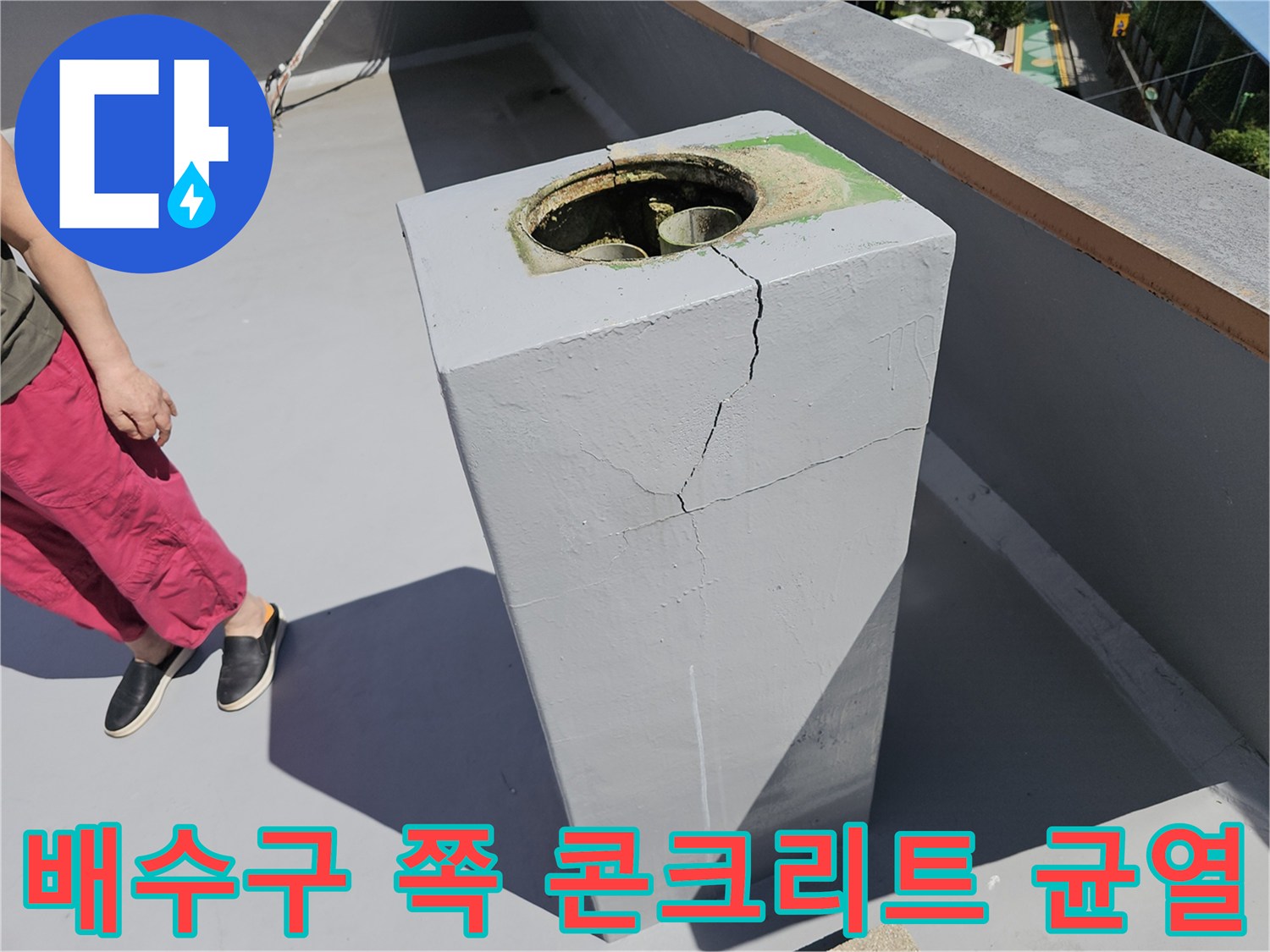 콘크리트 구조물의 수직 균열과 배수관 입구를 보여주는 사진입니다.