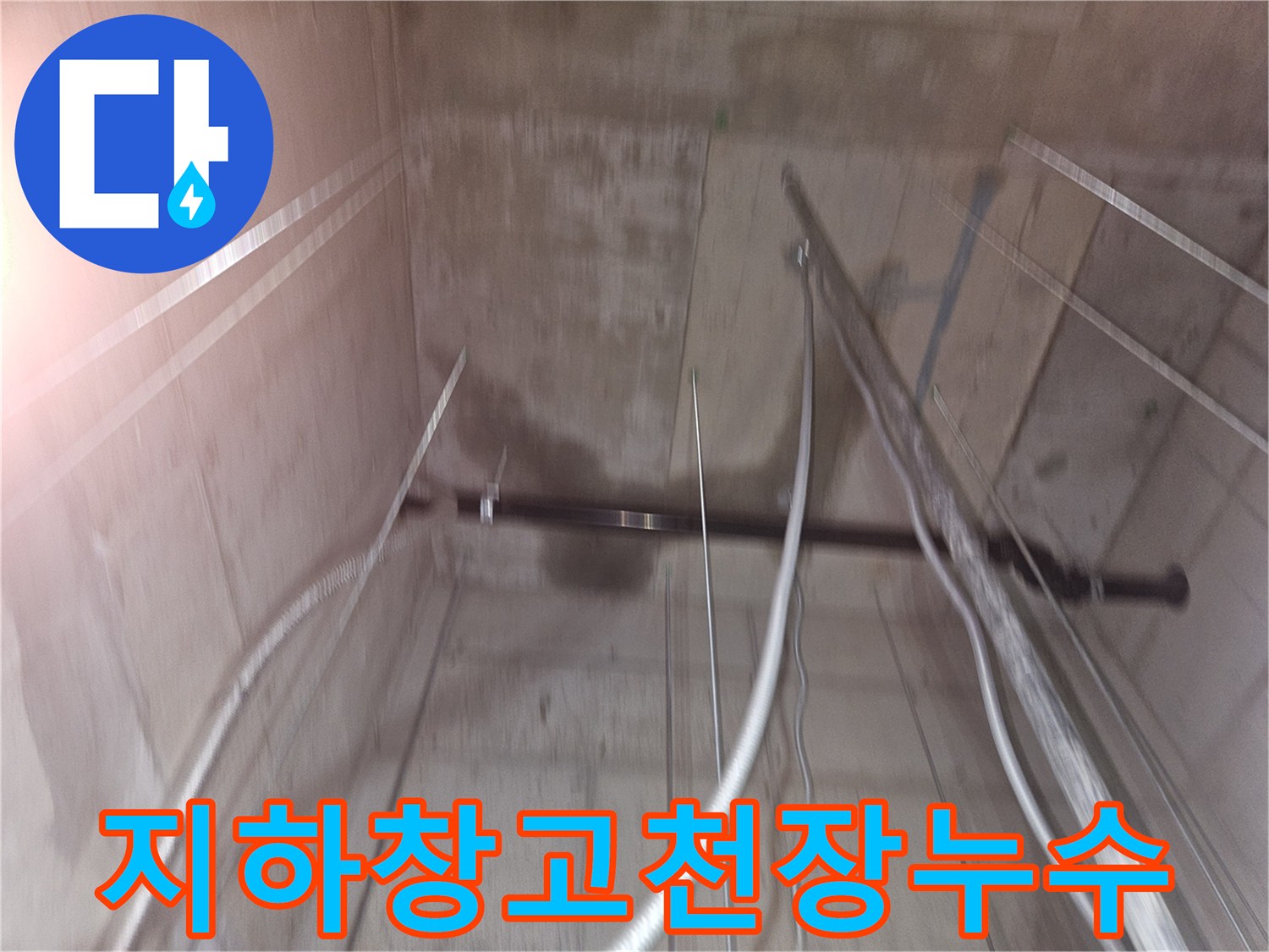 물에 젖어 변색된 지하 창고의 콘크리트 천장과 노출된 금속 배관