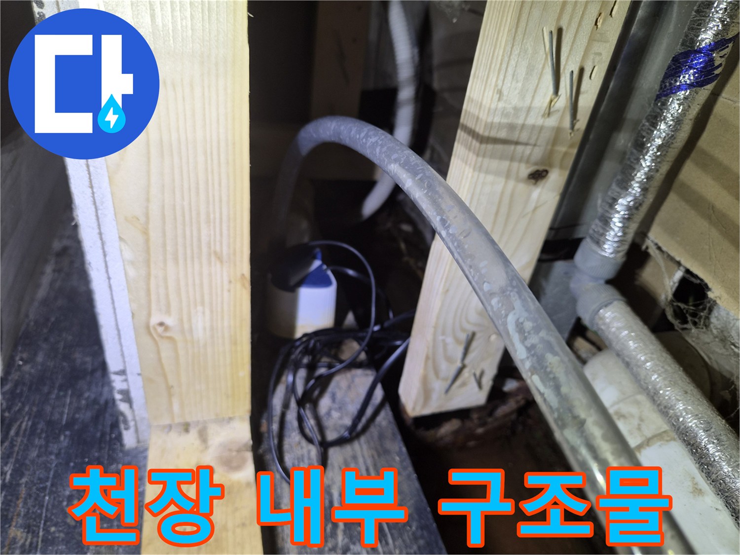 복잡한 배관과 목재 프레임이 겹쳐진 상가 천장 내부 모습