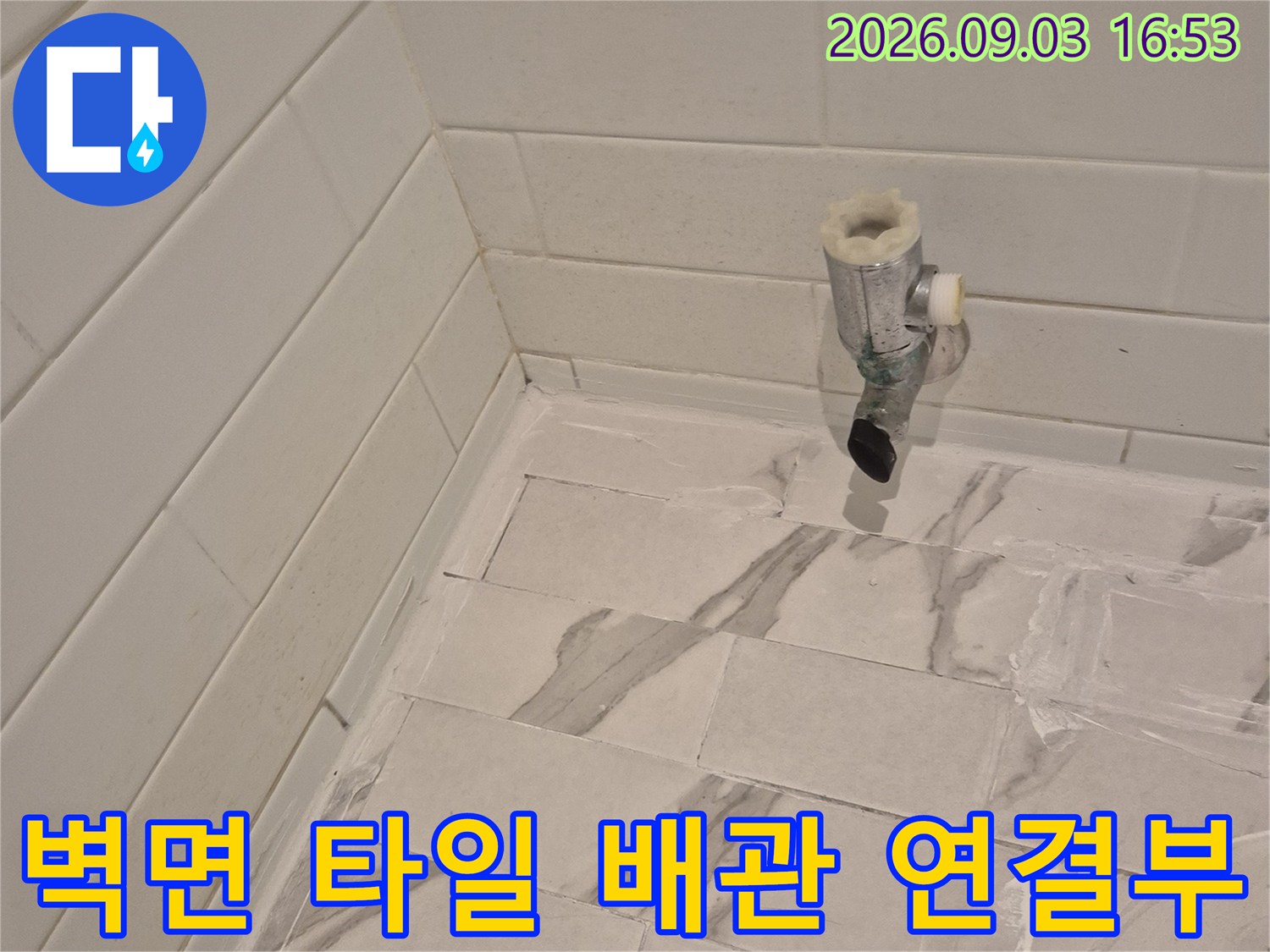 대리석 패턴 타일 벽면에 설치된 수도 밸브 부근 상세 사진