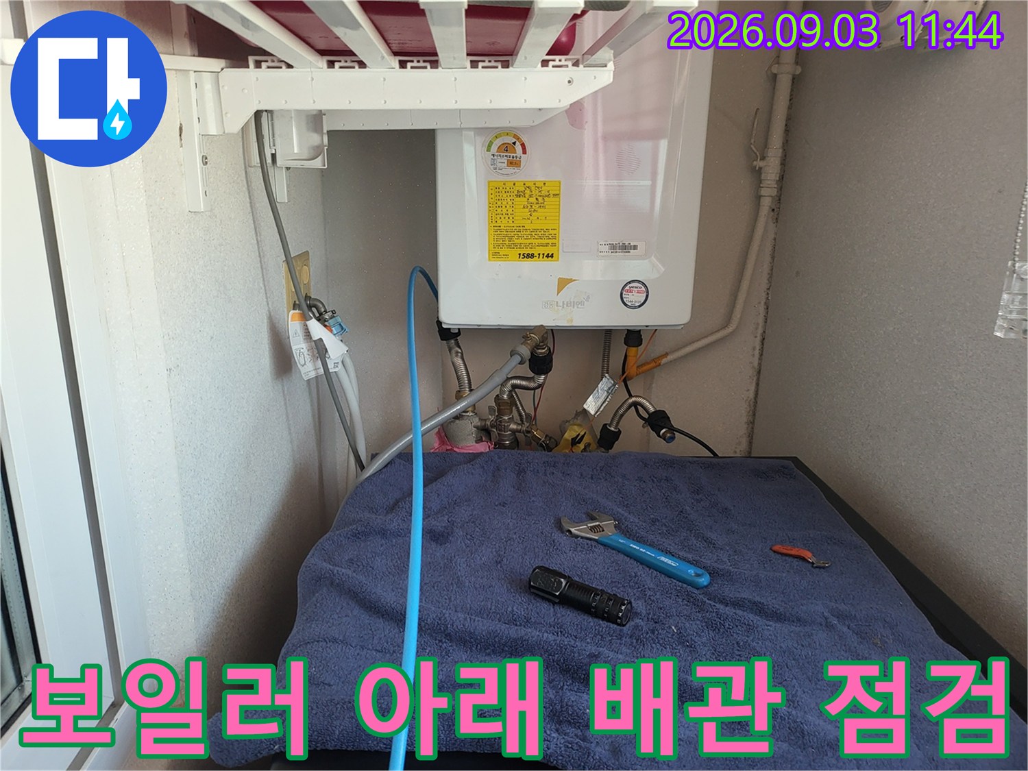 보일러 하단부의-배관 연결 상태와 작업용 도구 배치 모습