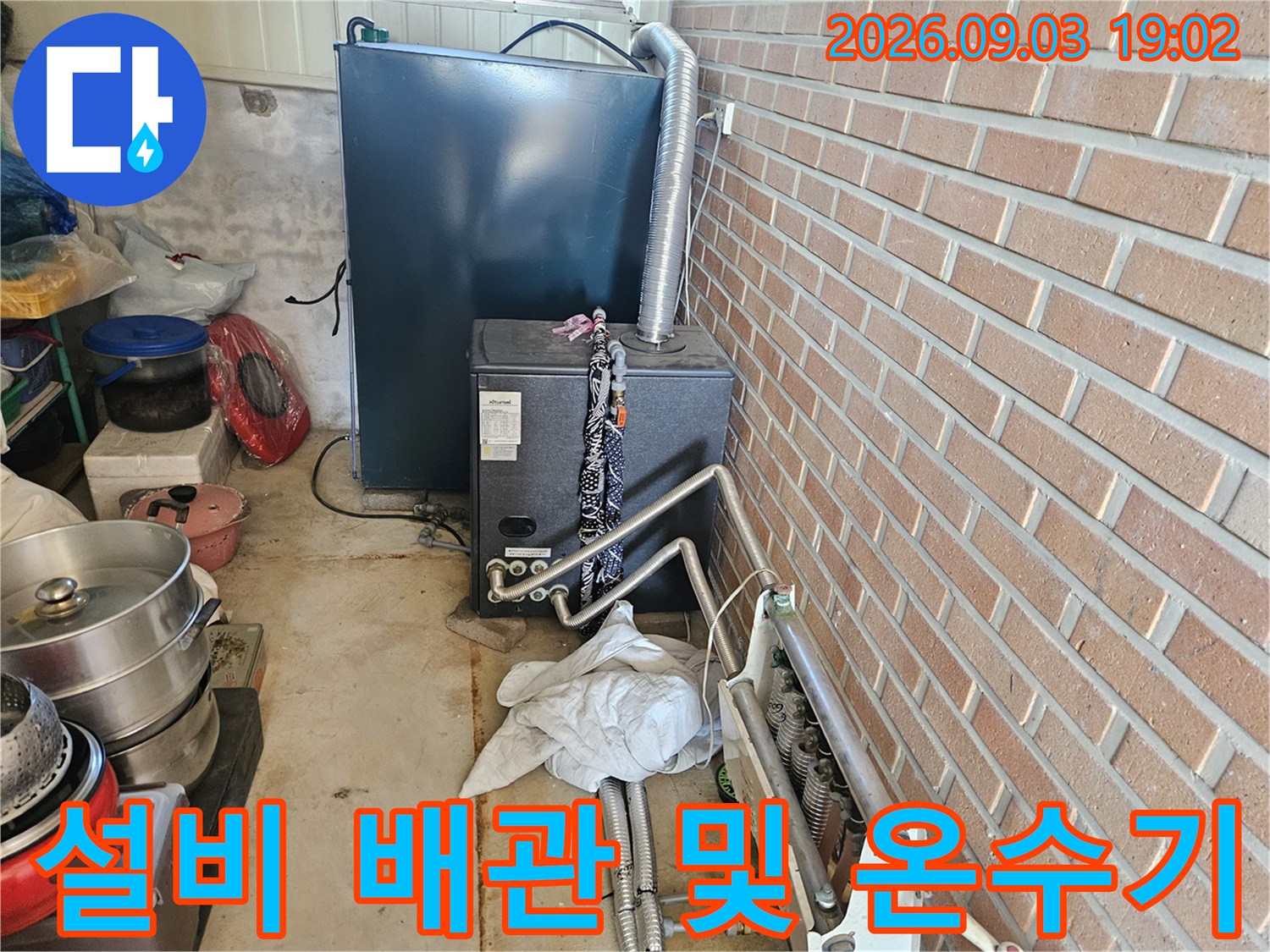 보일러실 내 설치된 대형 온수기와 하단 금속 배관의 모습입니다.