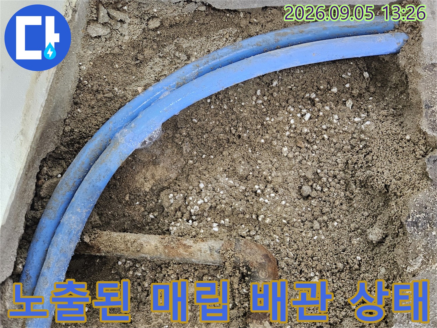 벽체 굴착 부위에 드러난 파란색 배관과 금속 연결재