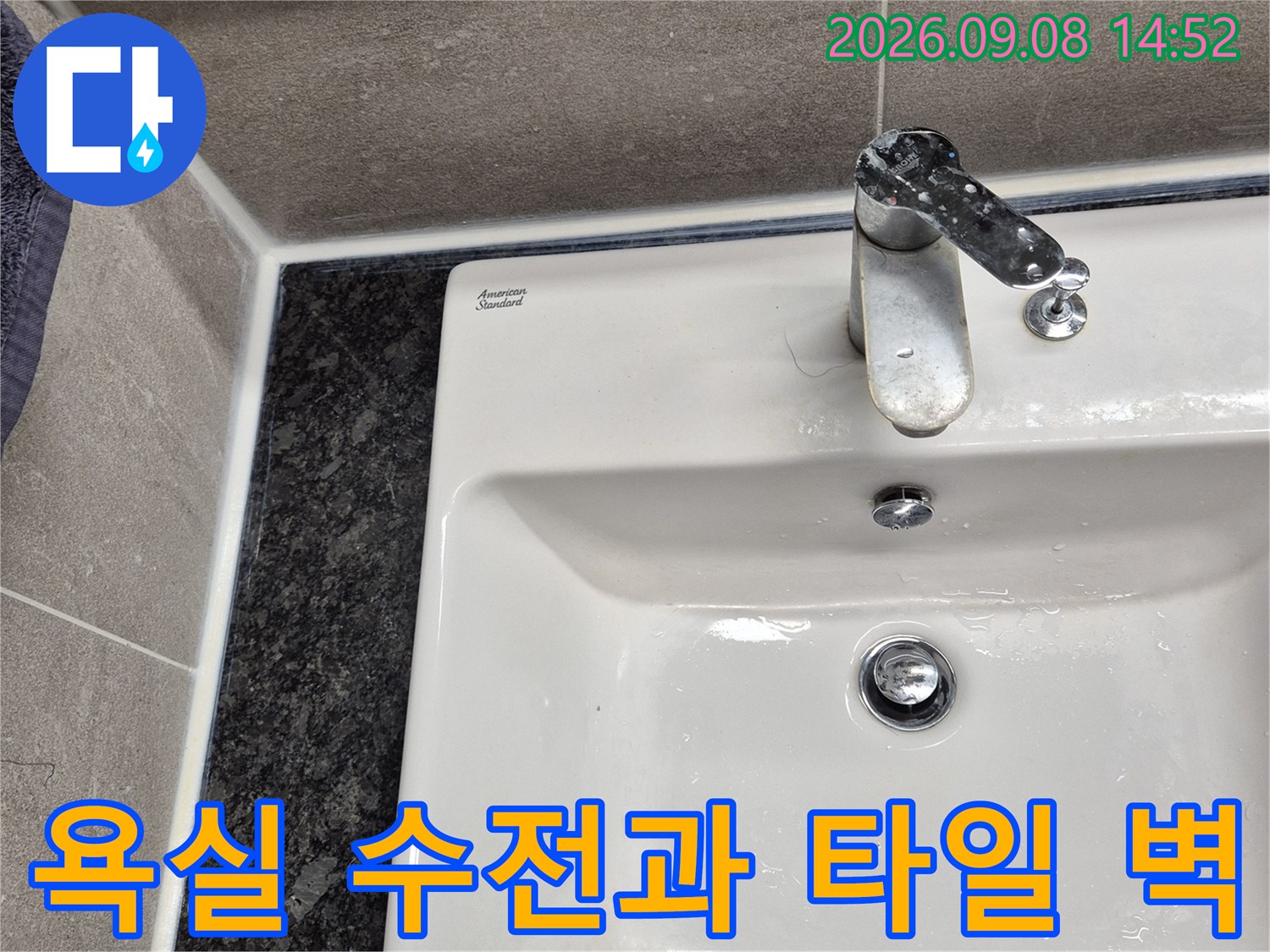 금속 재질의 수전과 회색 욕실 타일