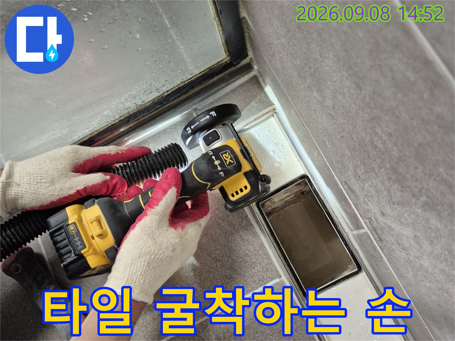 장갑을 낀 작업자가 드릴로 타일을 제거하는 모습