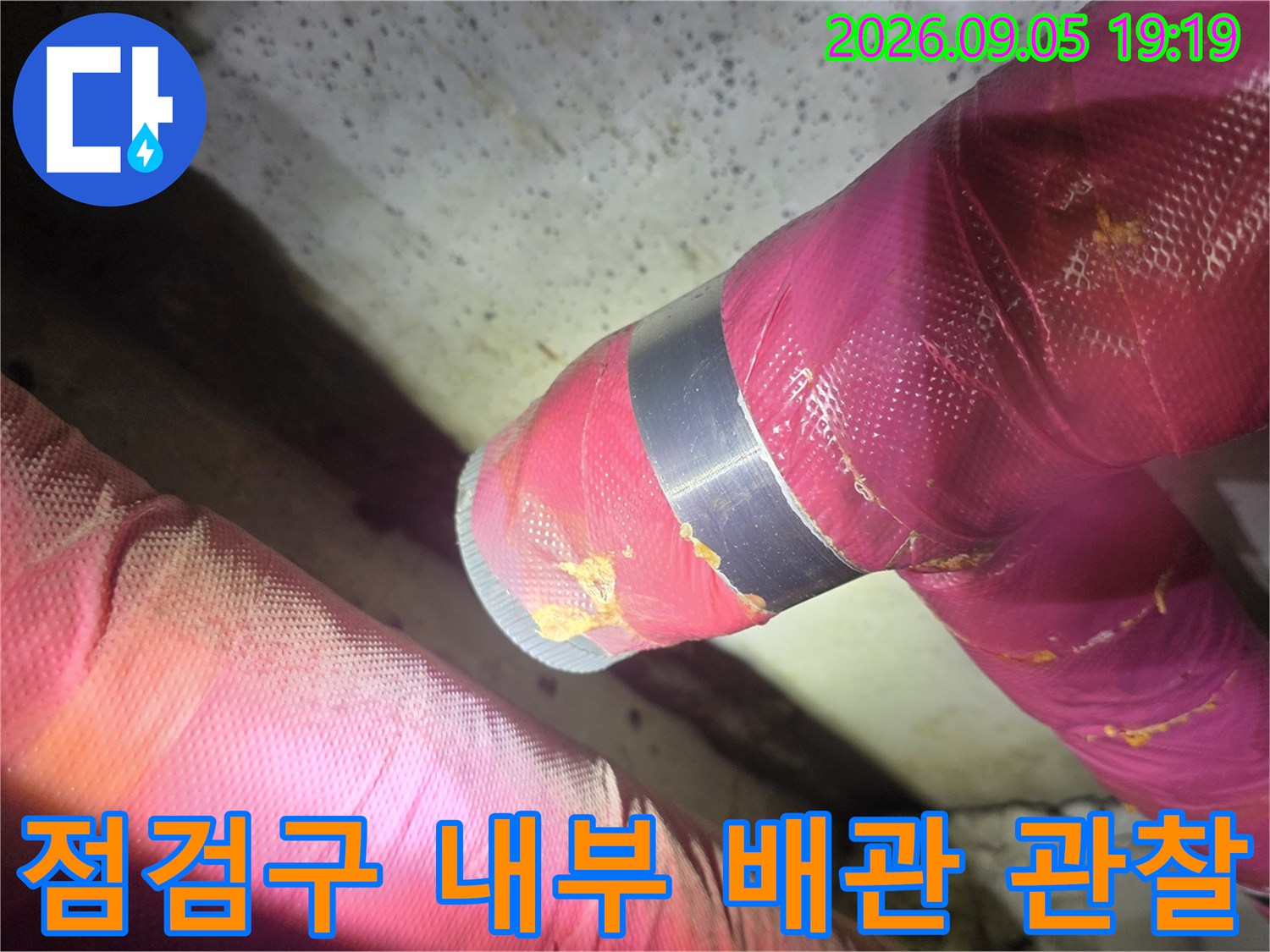 화장실 천장-분홍색 보온재로 감싸진 배관의 근접 촬영