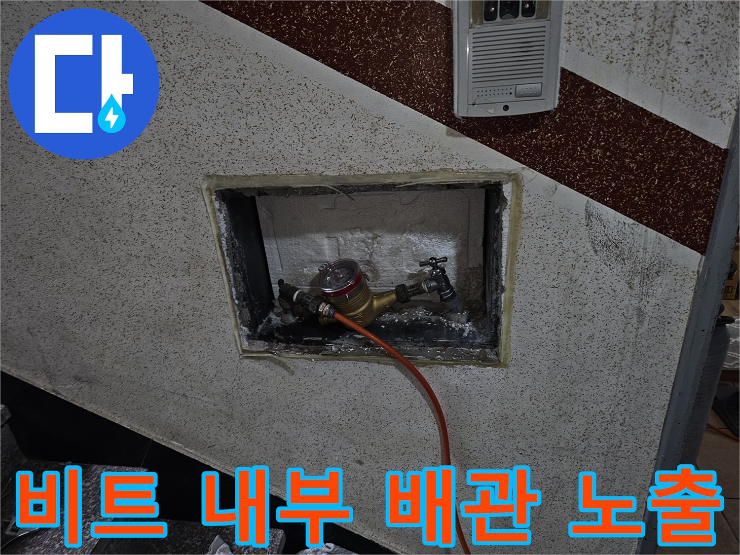 벽면 타공 부위를 통해 보이는 수도 계량기 및 밸브 장치