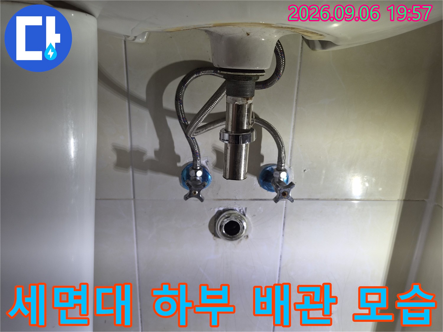 세면대 아래 벽면에 설치된 수전 밸브와 배관 연결 부위