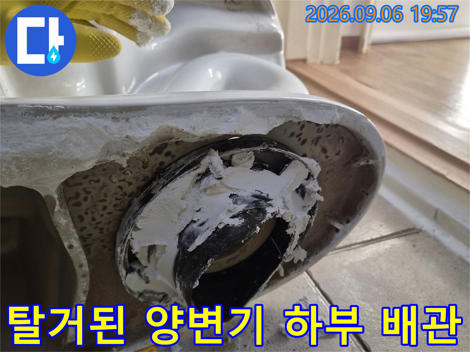 양변기 탈거 후 드러난 배수구 부속과 젖은 타일 주변 상황