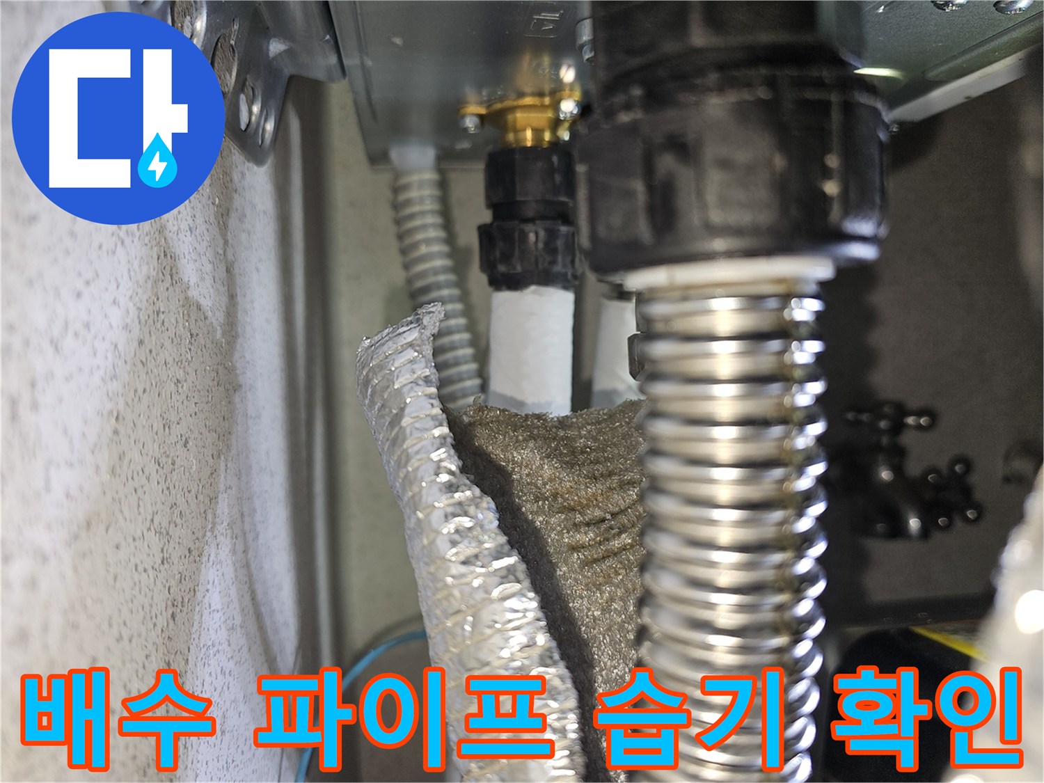 배수관 연결부-습기에 노출된 은색 주름관과 검은색 부속품