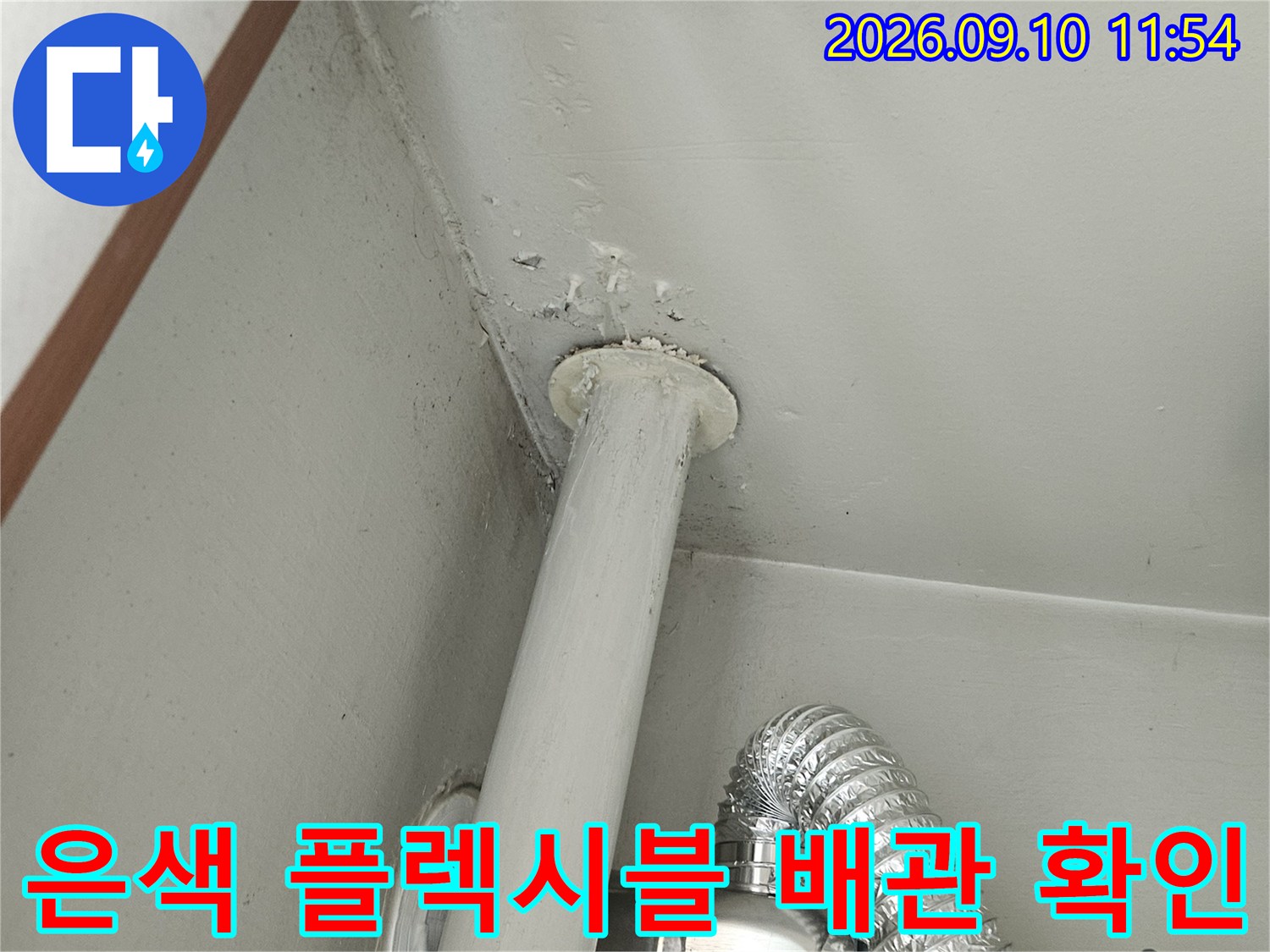 천장에 설치된 은색 자재의 유연한 배관과 연결 부위 상세 사진입니다.