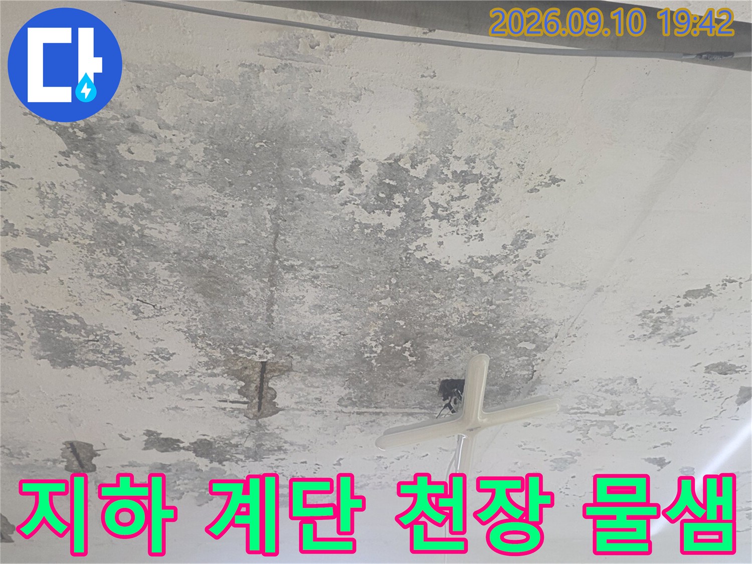 지하 계단 천장-넓게 퍼진 누수 얼룩과 배관 흔적