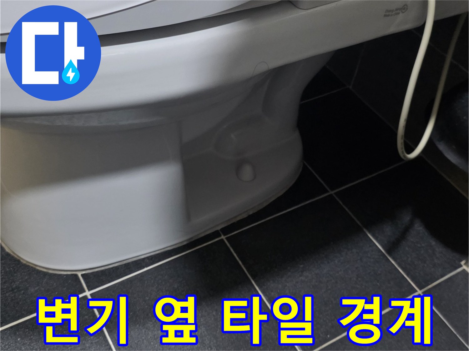 변기 하단과 어두운 색 타일의 접합 부위 사진입니다.