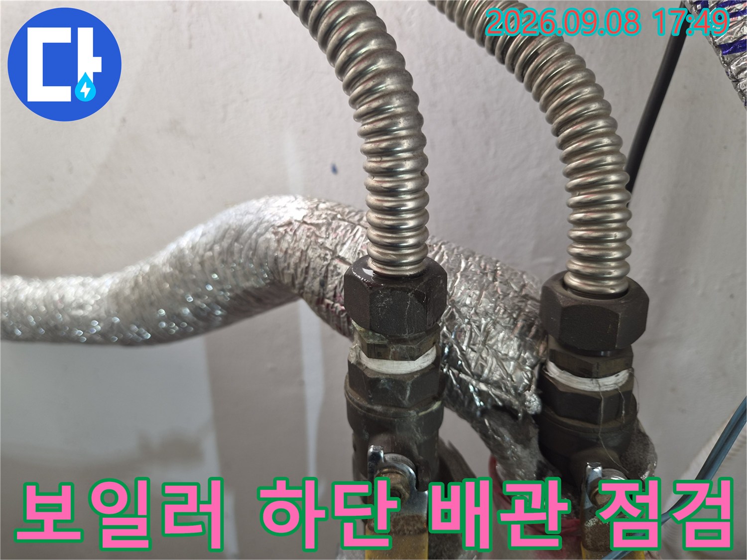 보일러 아래쪽 금속 주름관과 은박 보온재가 씌워진 배관 상세 사진